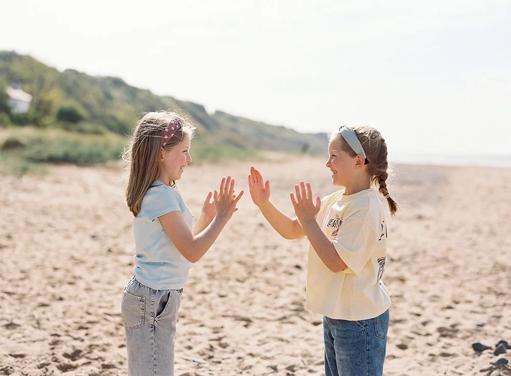 natural photograph of two sisters playing together at the beach on the Wirral
