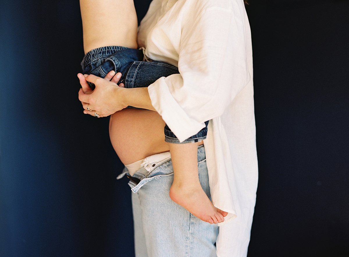 Photograph of a Mum-to-be carrying her son on her bump at home
