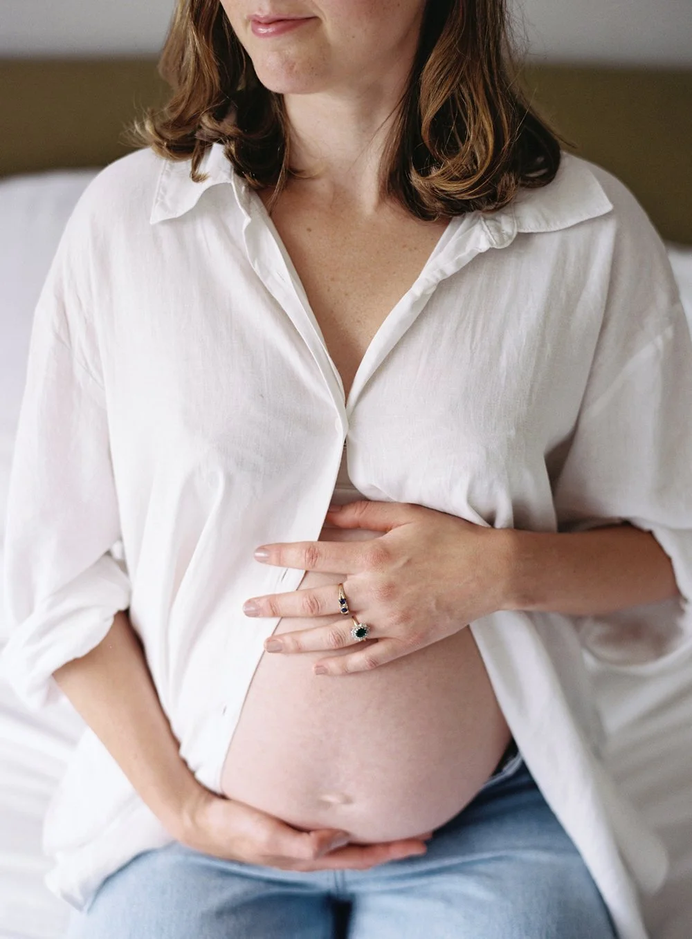 Photograph of a mum-to-be in an oversized white shirt holding her bump