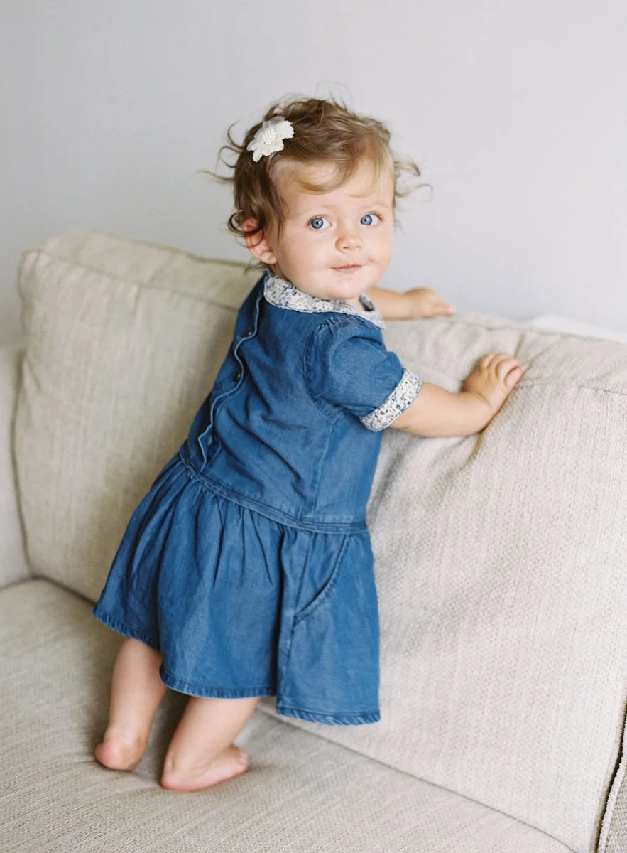 candid portrait of a toddler standing on the sofa at home