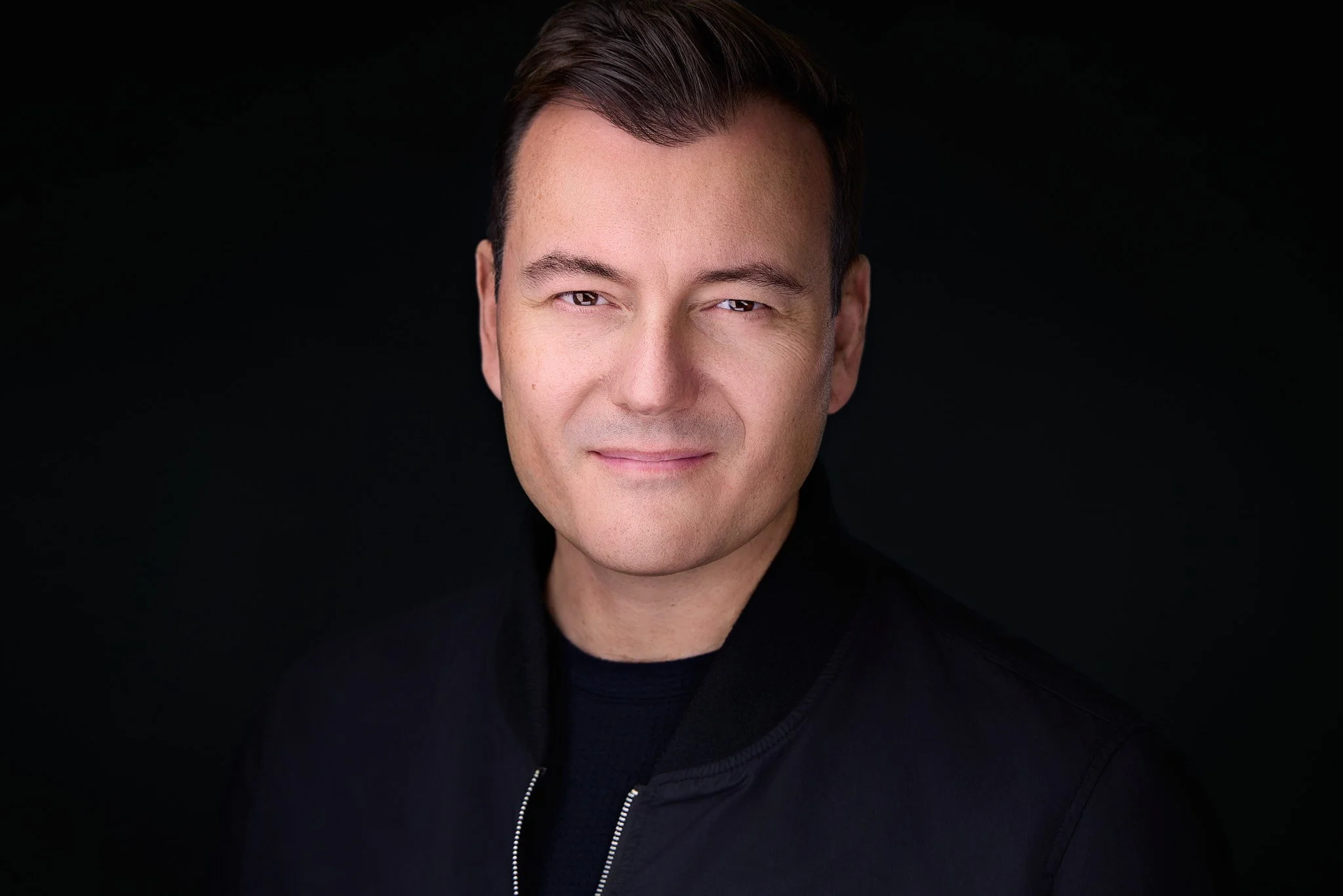 Contemporary professional headshot with a confident, relaxed expression.