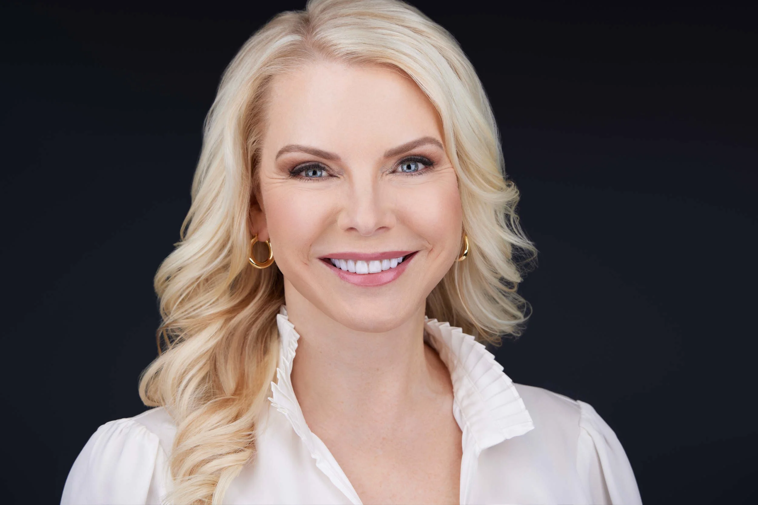 Professional headshot of a woman in a white blouse with a warm, approachable expression.