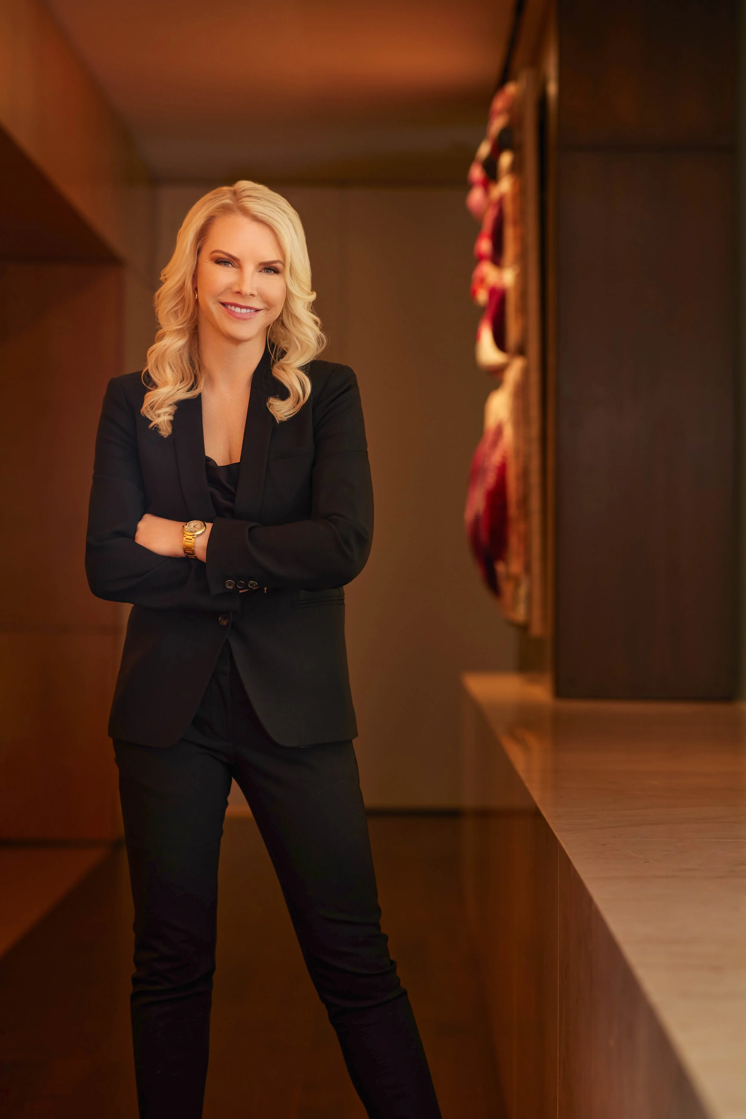 Professional environmental portrait of a woman in a black blazer with a warm, confident expression.