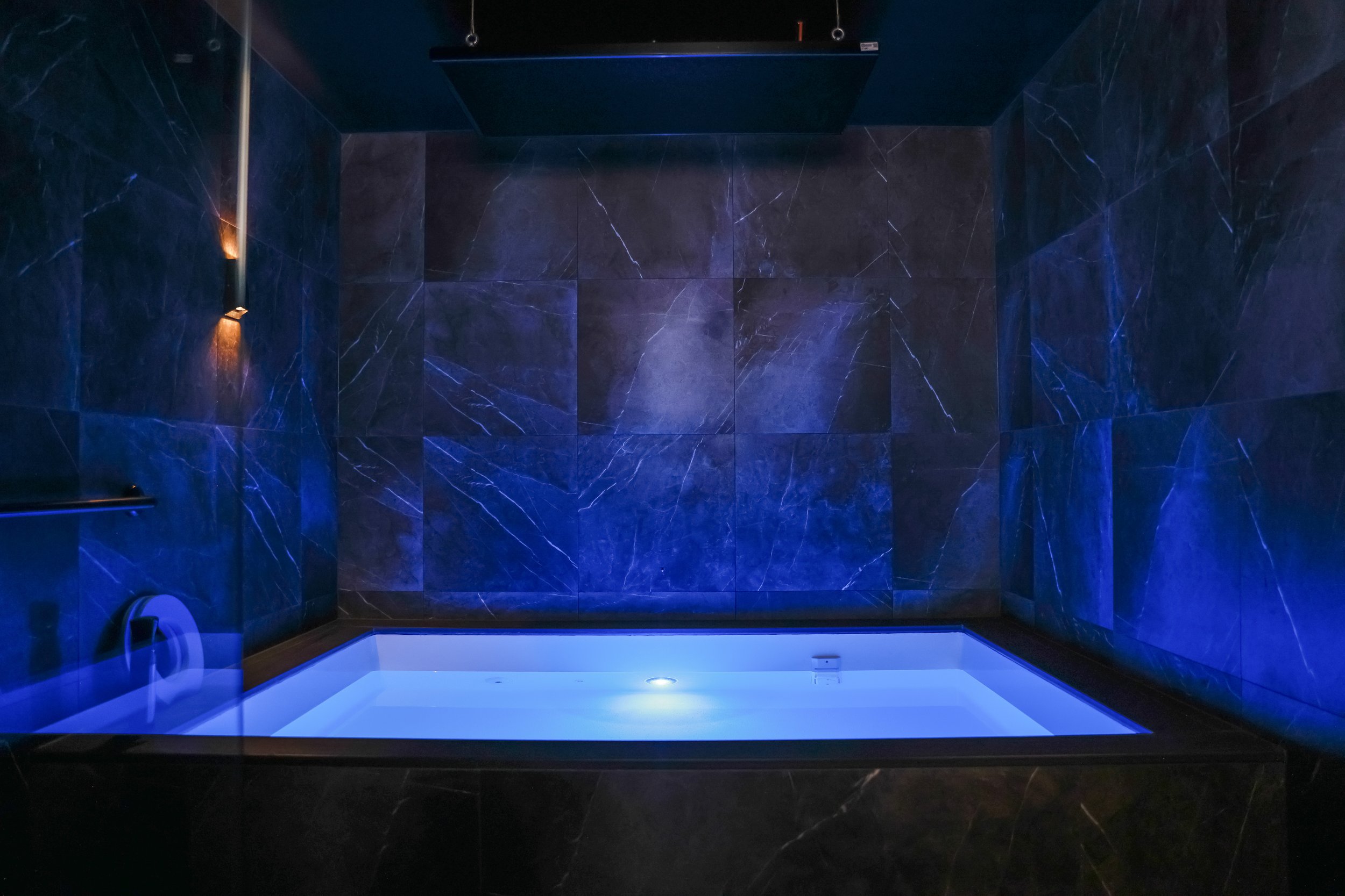 Float therapy tank in a calming blue-lit room for relaxation and better sleep