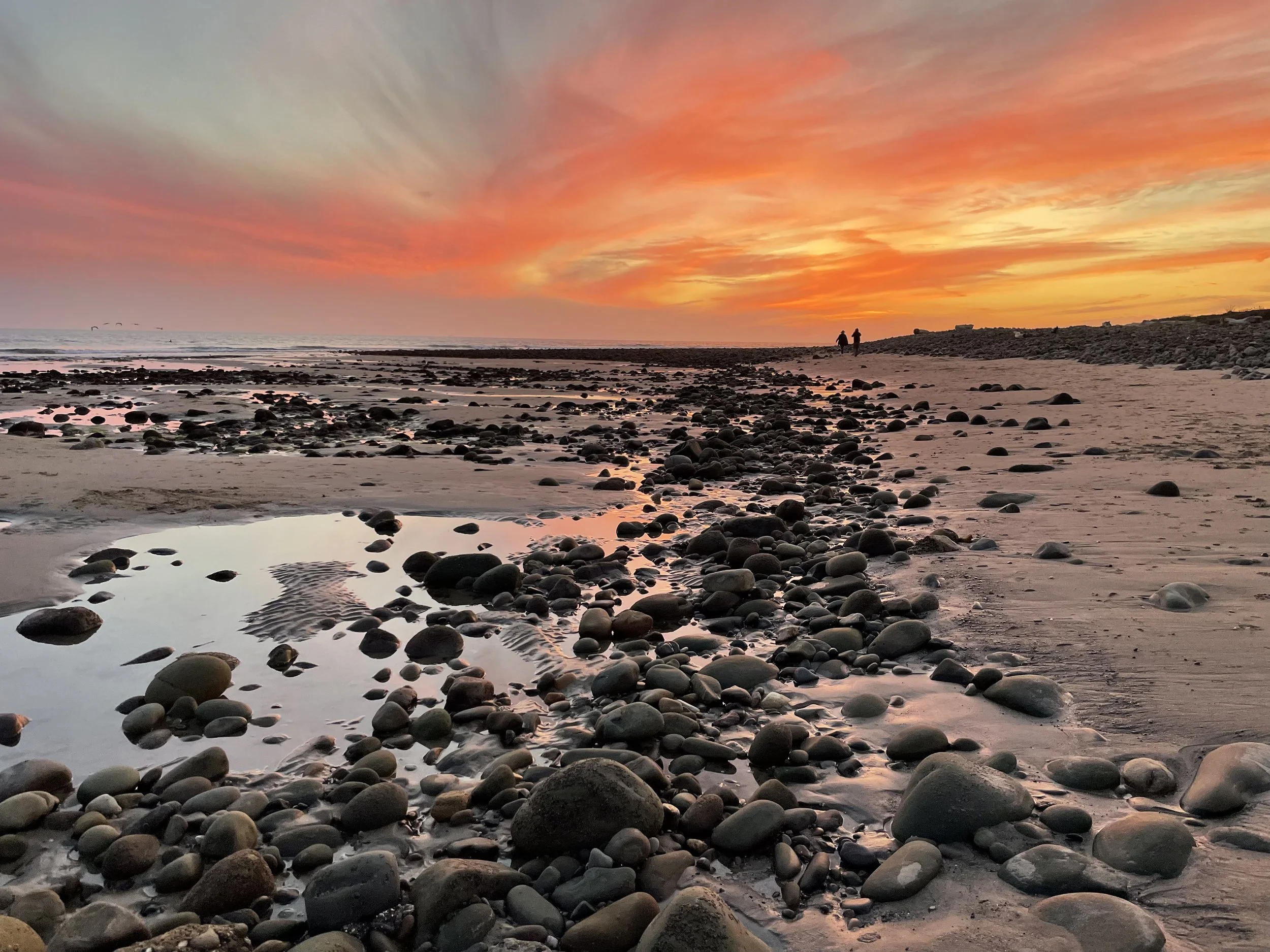Surfer’s Point at low tide in Ventura at sunset with two people walking in the distance.