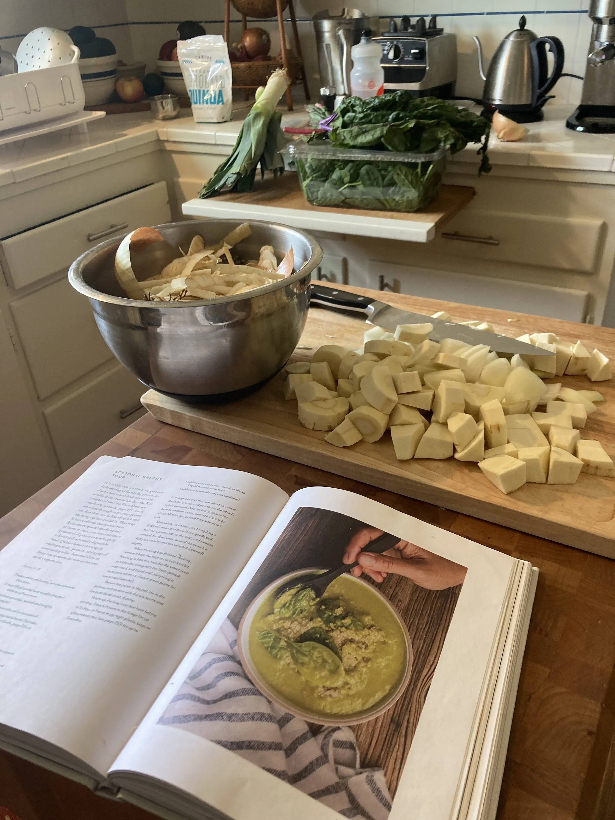 First Forty Days cookbook open on the counter with chopped turnips and leeks in preparation for postpartum nutrition session.