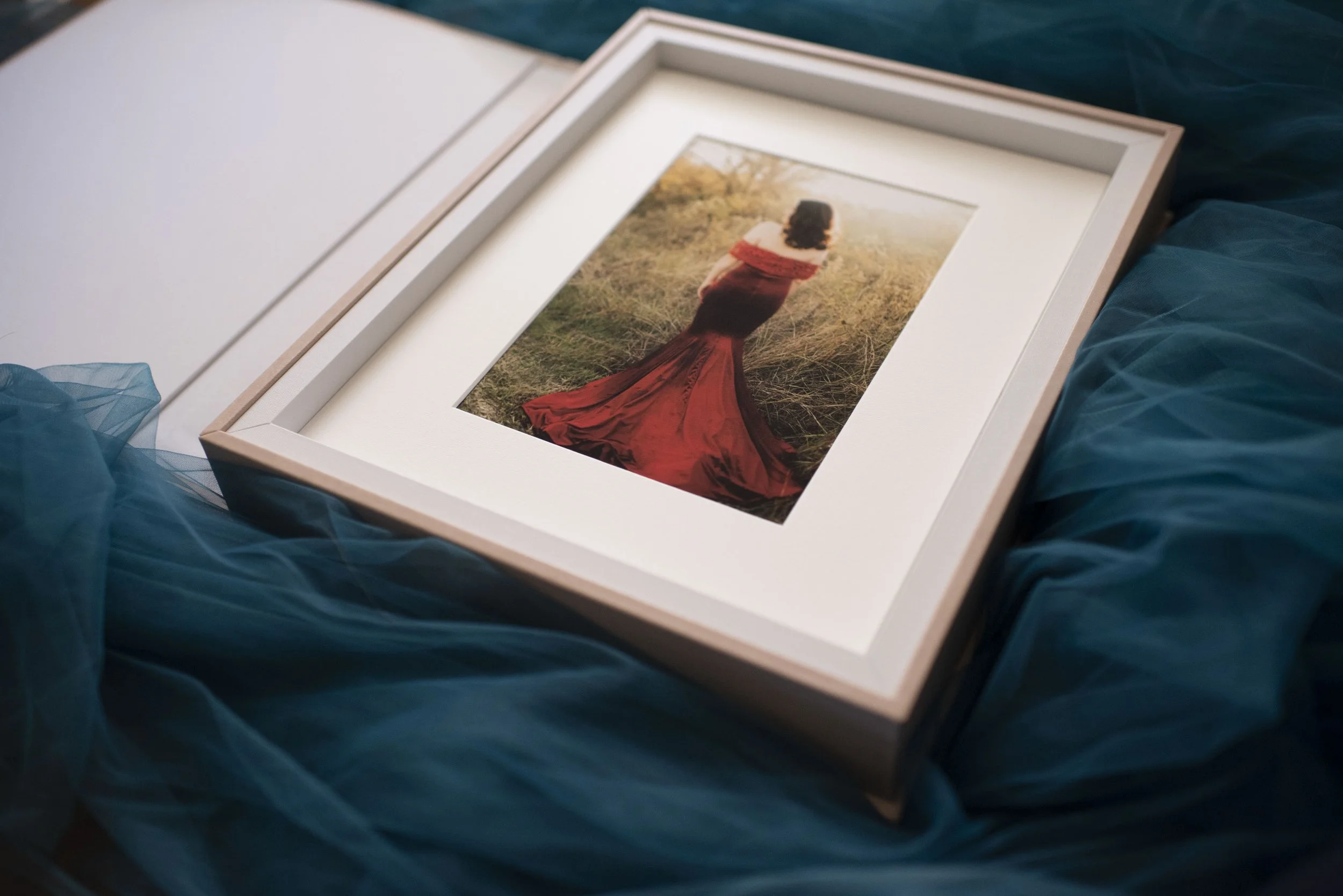 Framed Folio Box prints of a woman in a red dress sitting in a grassy field.