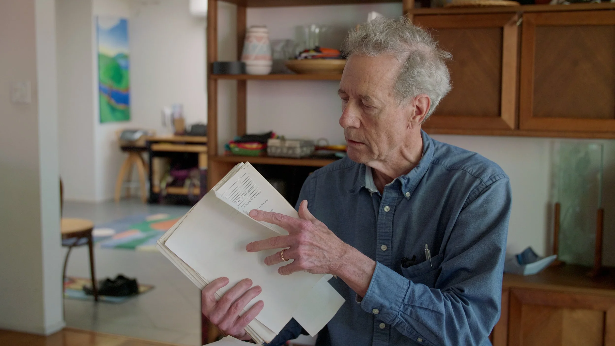 Elderly man reading a document in a home office setting