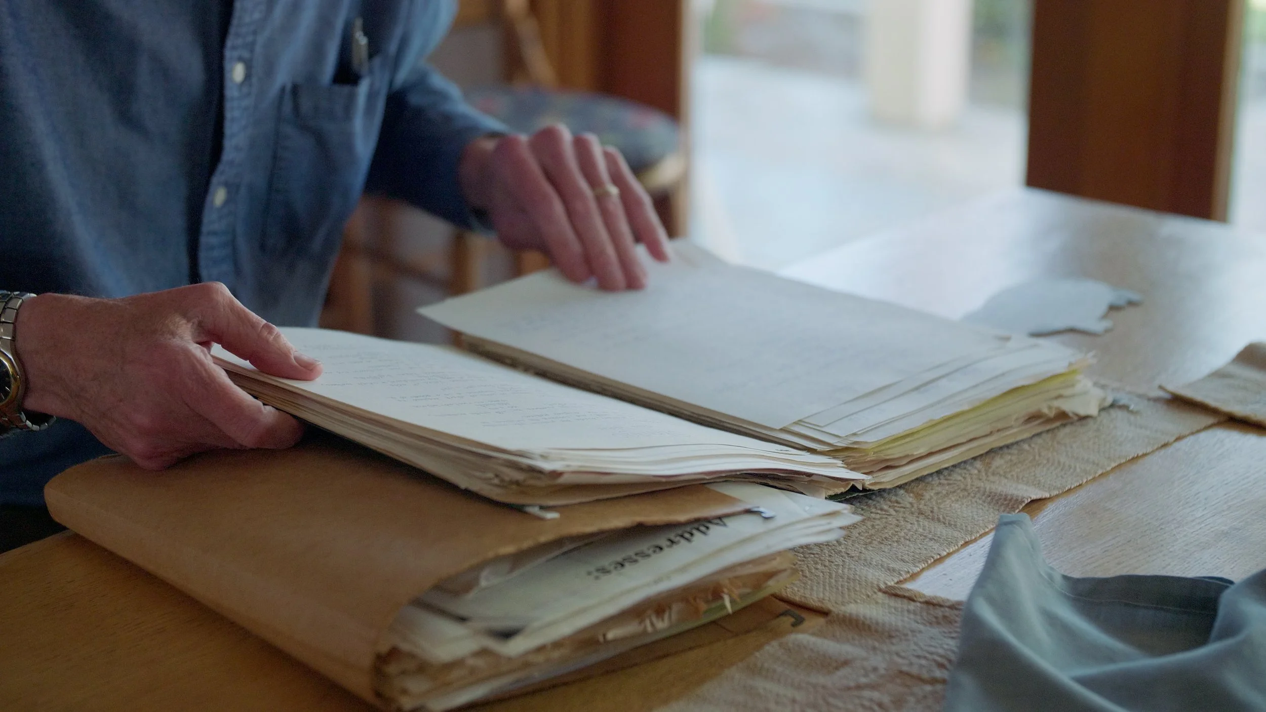 Person organizing papers on a wooden table