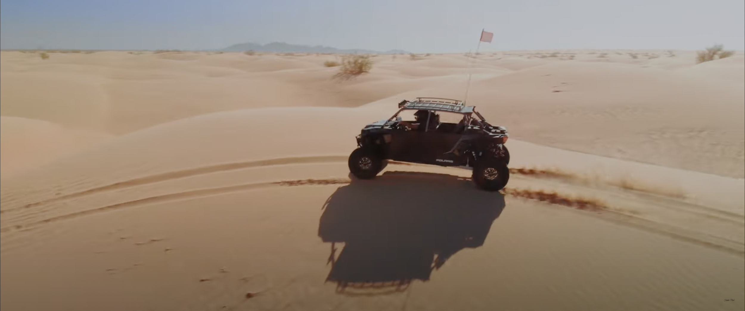 Off-road vehicle driving through desert sand dunes.