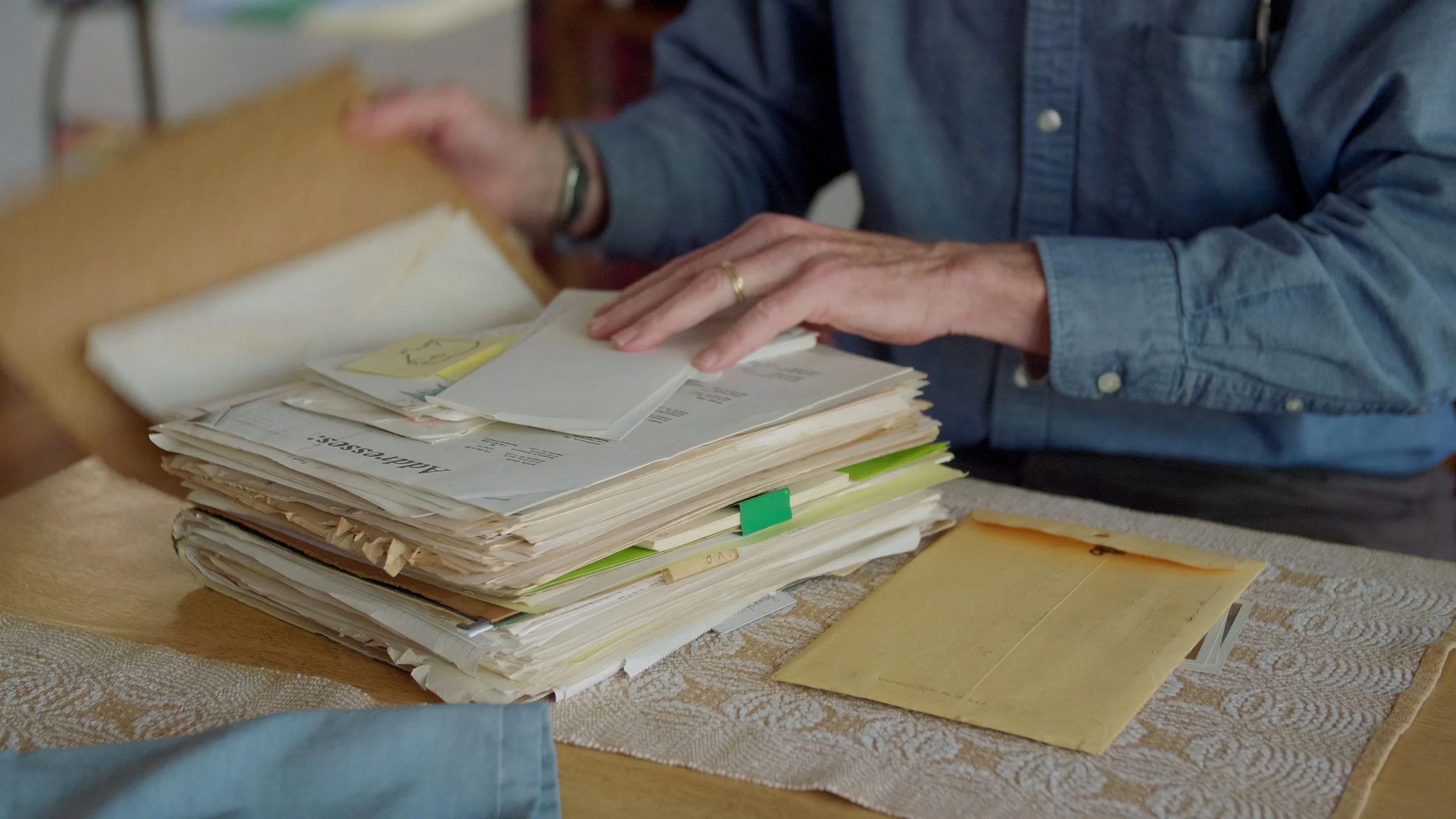 Person sorting through documents and envelopes on a table.