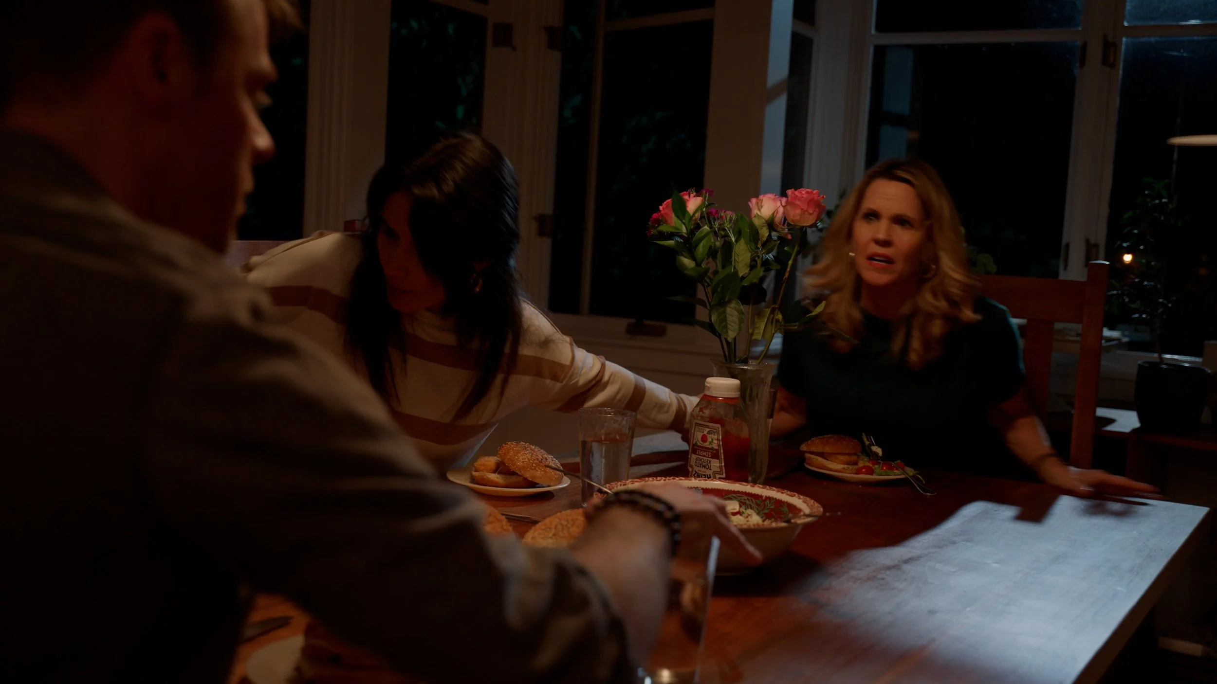 People sitting at a dinner table with food and flowers