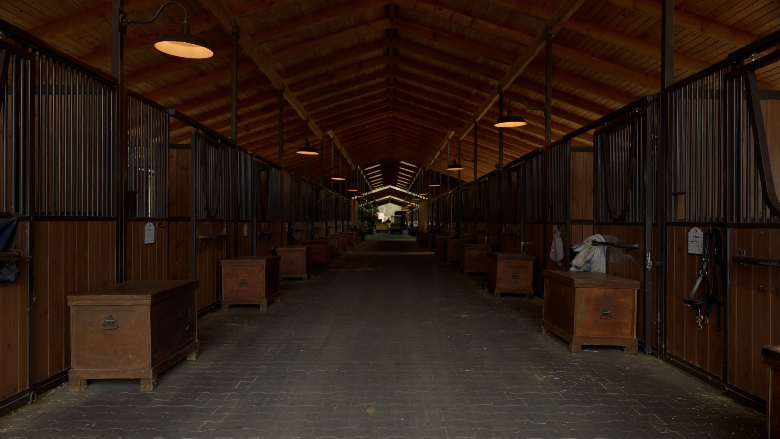 Interior of a wooden horse stable with stalls on both sides.
