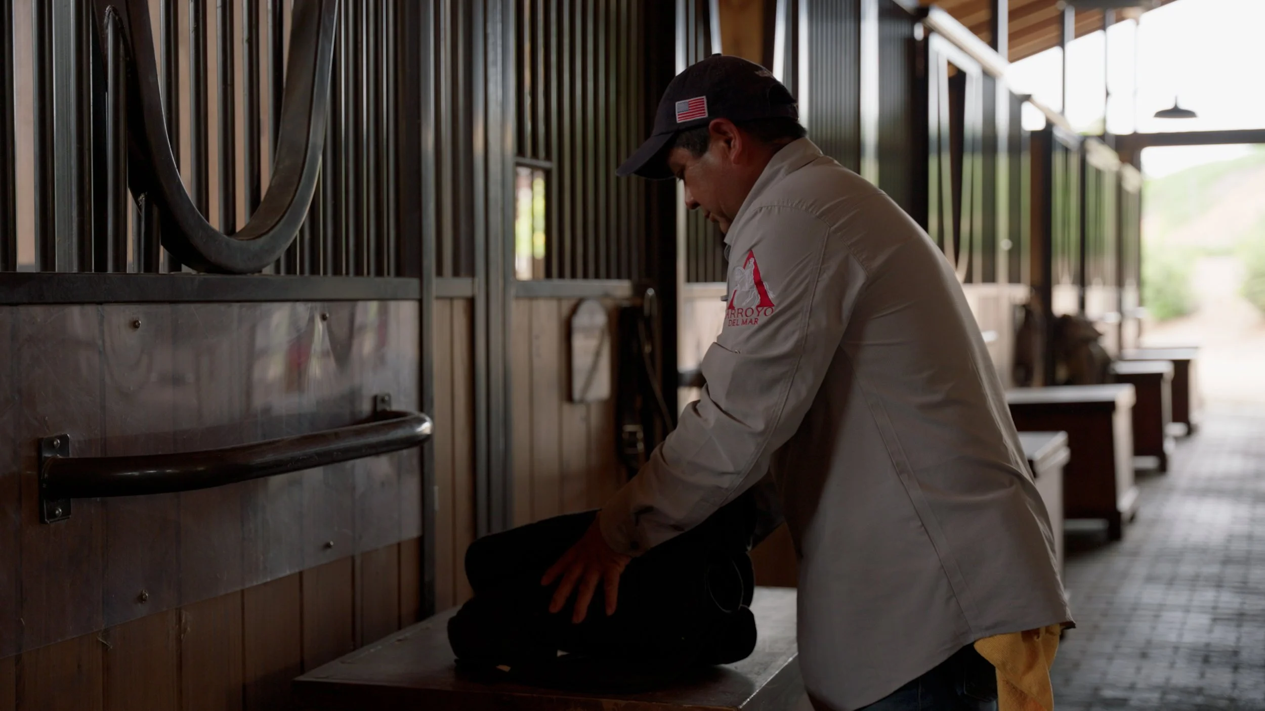 Person arranging equipment in a horse stable.