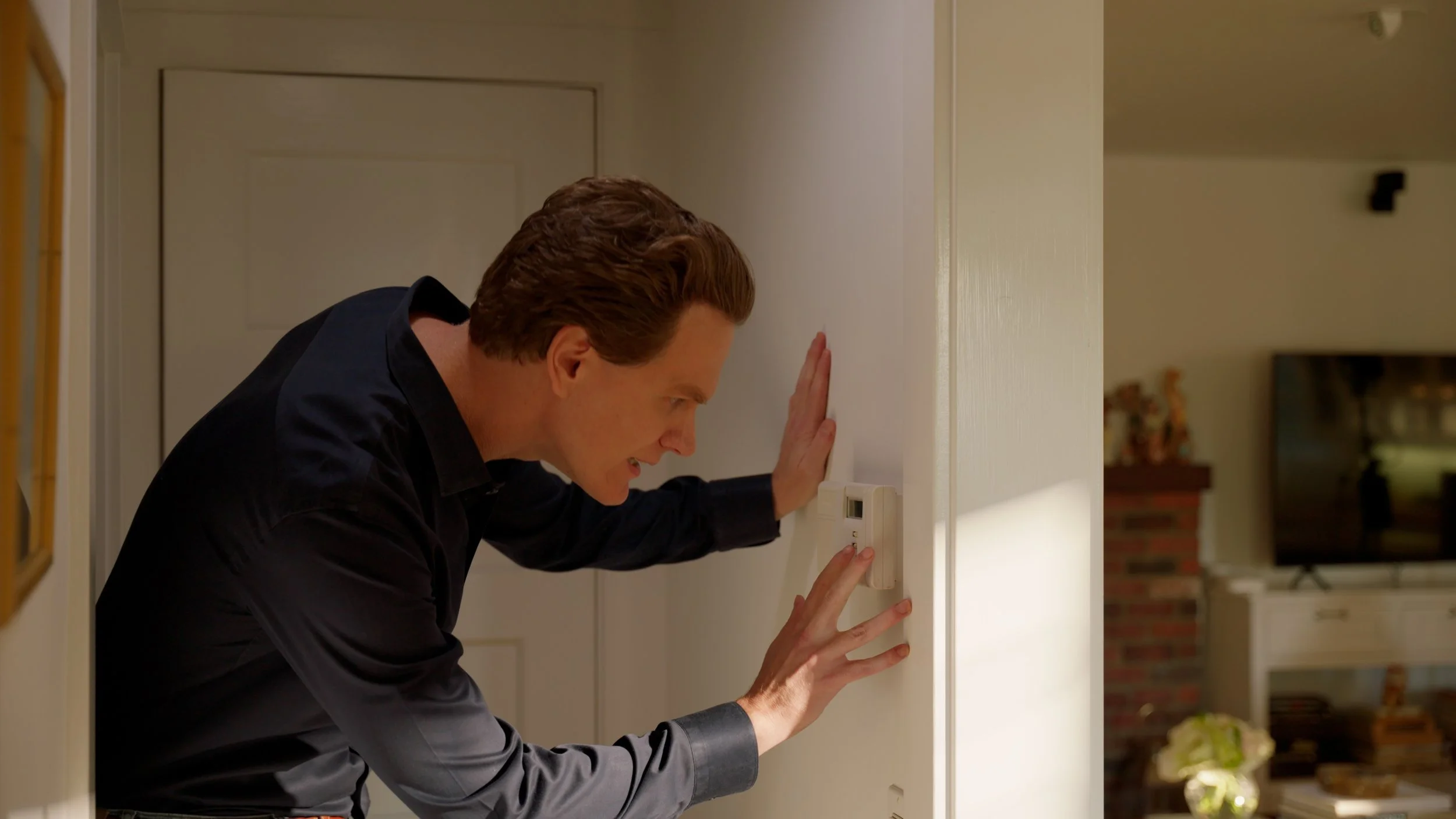Person adjusting thermostat on wall inside home