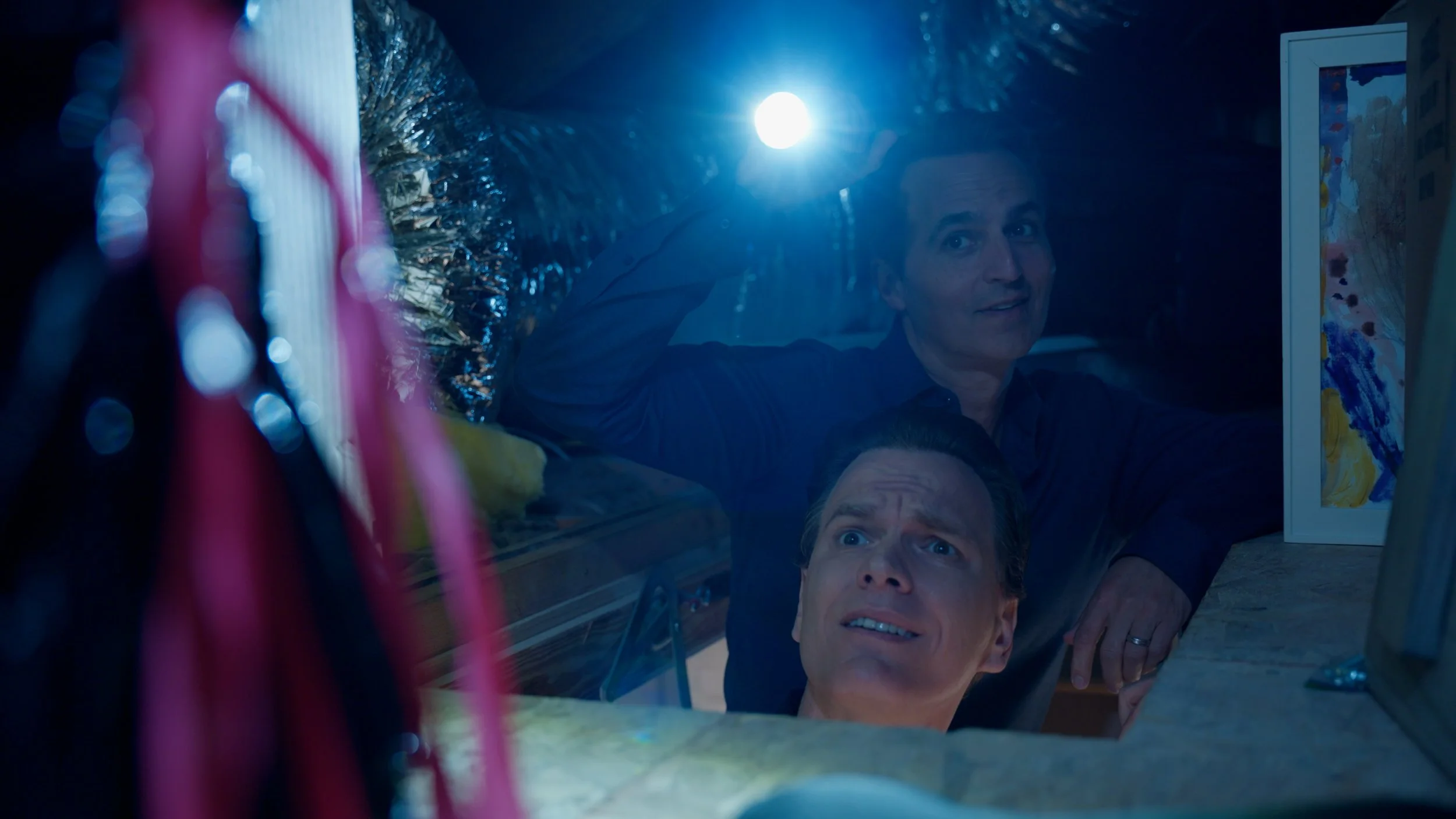 Two people in dark room with flashlight, looking upwards