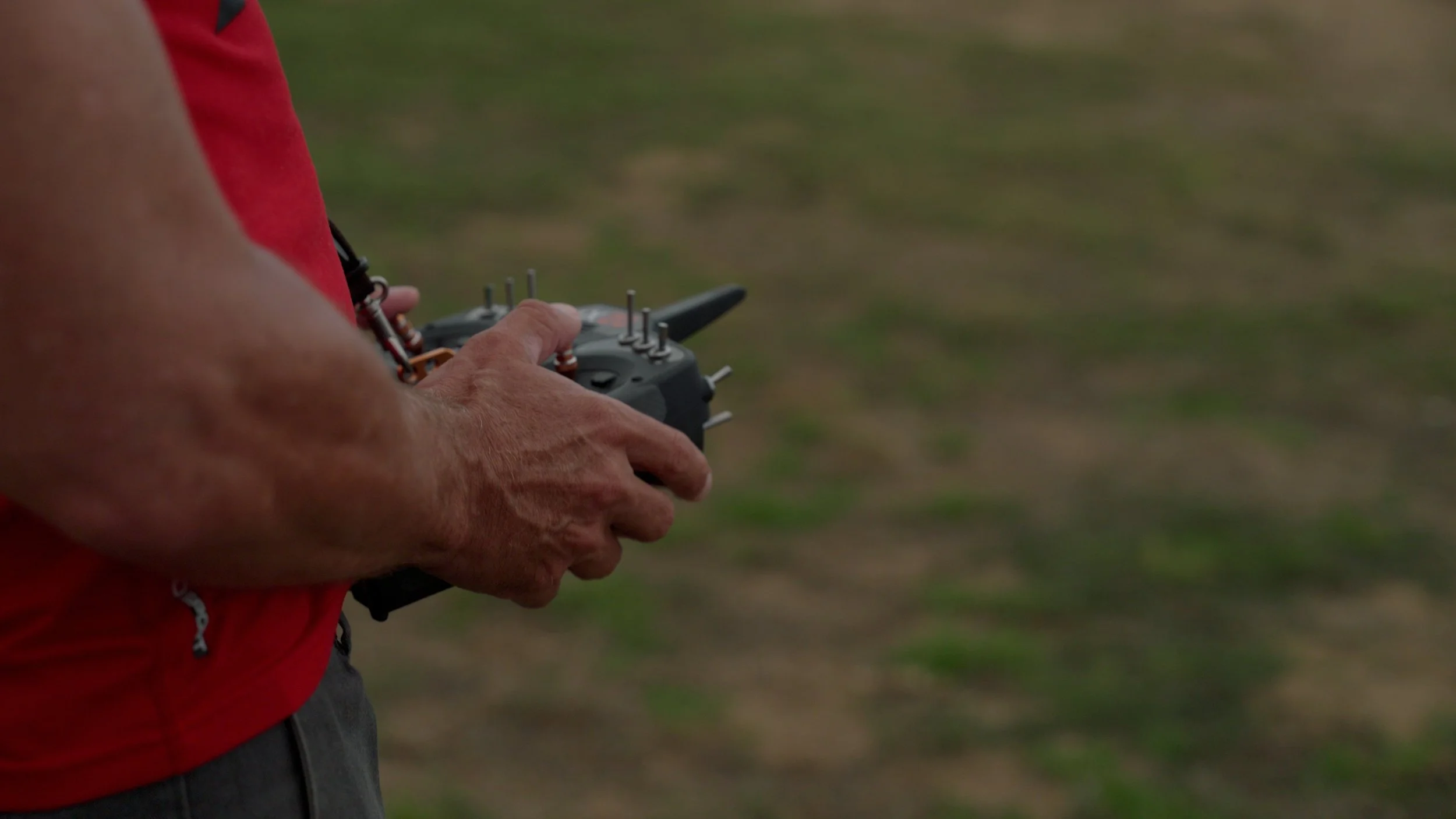 Person holding a remote control in a field