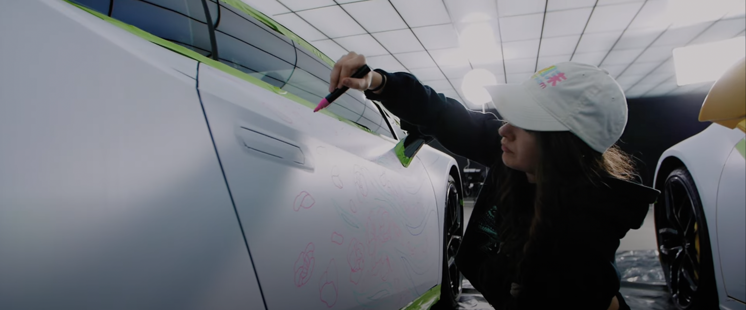 Person drawing on a car with pink marker