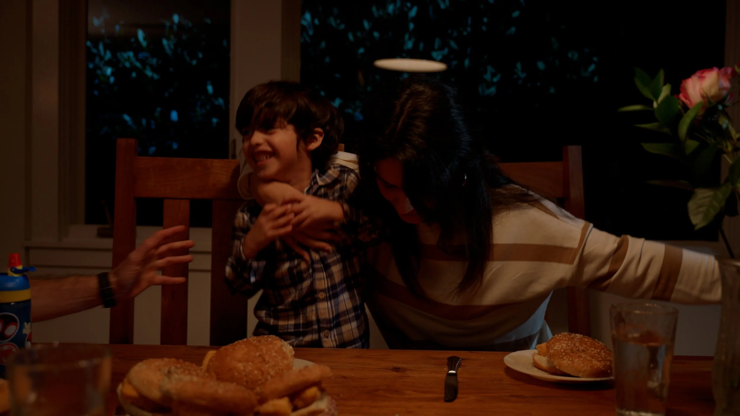 Family at dinner table with burgers and flowers in a vase