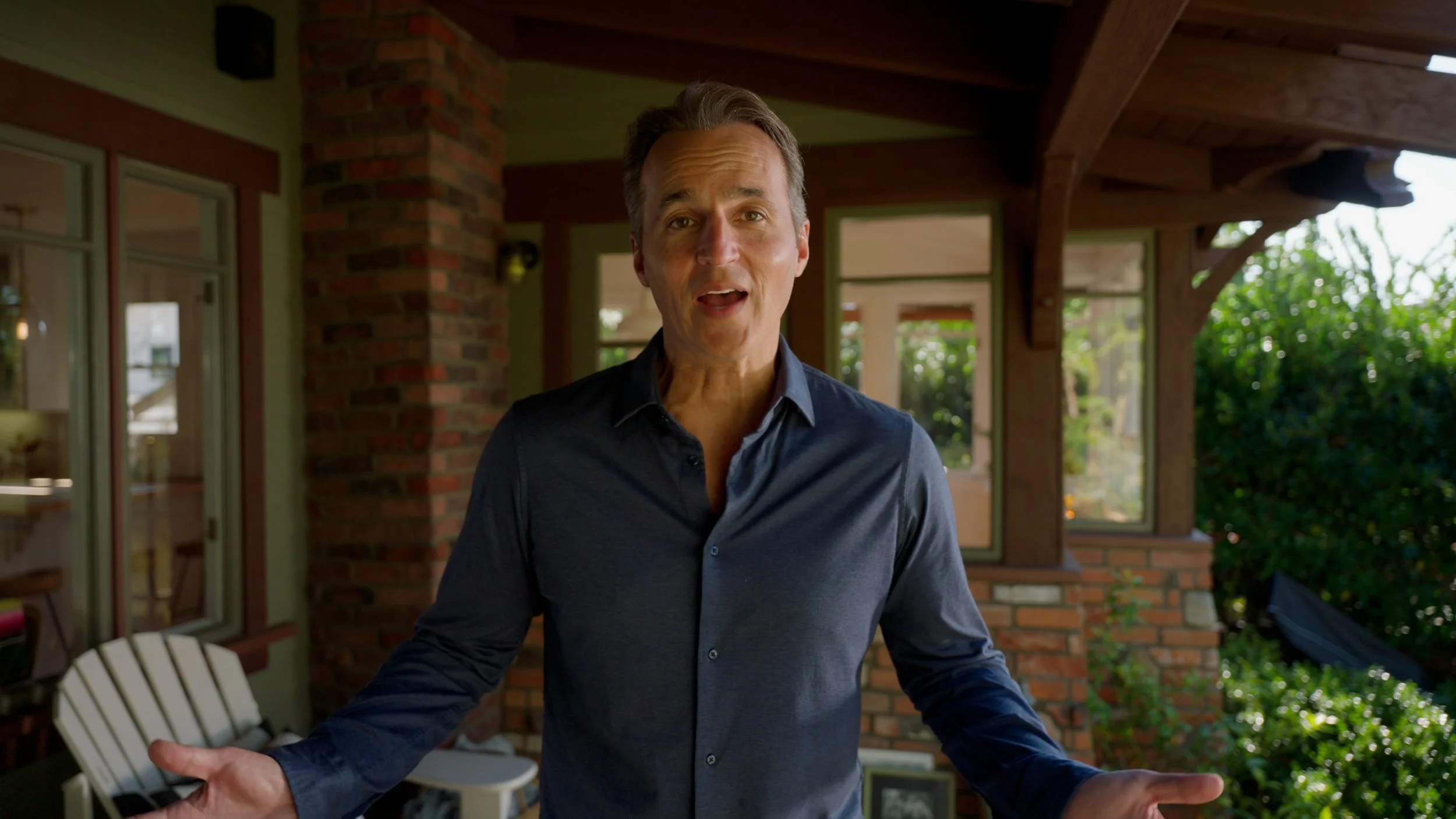Man standing on a porch with brick and glass walls.