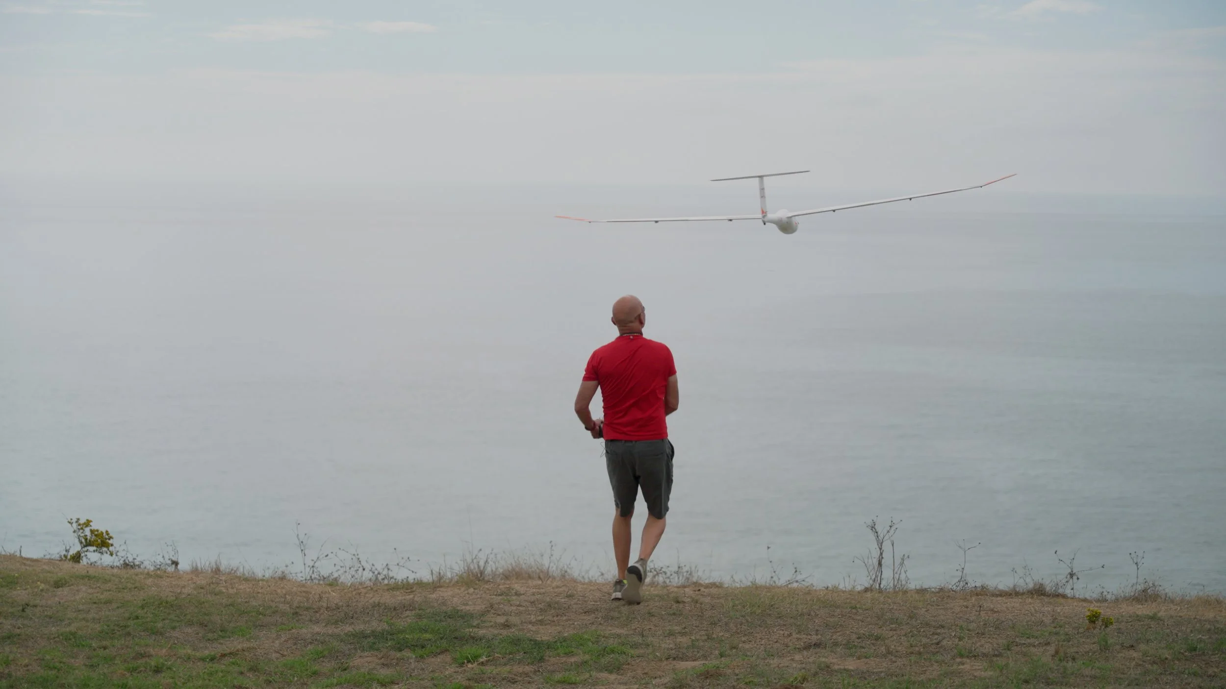 Person watching remote control glider over water