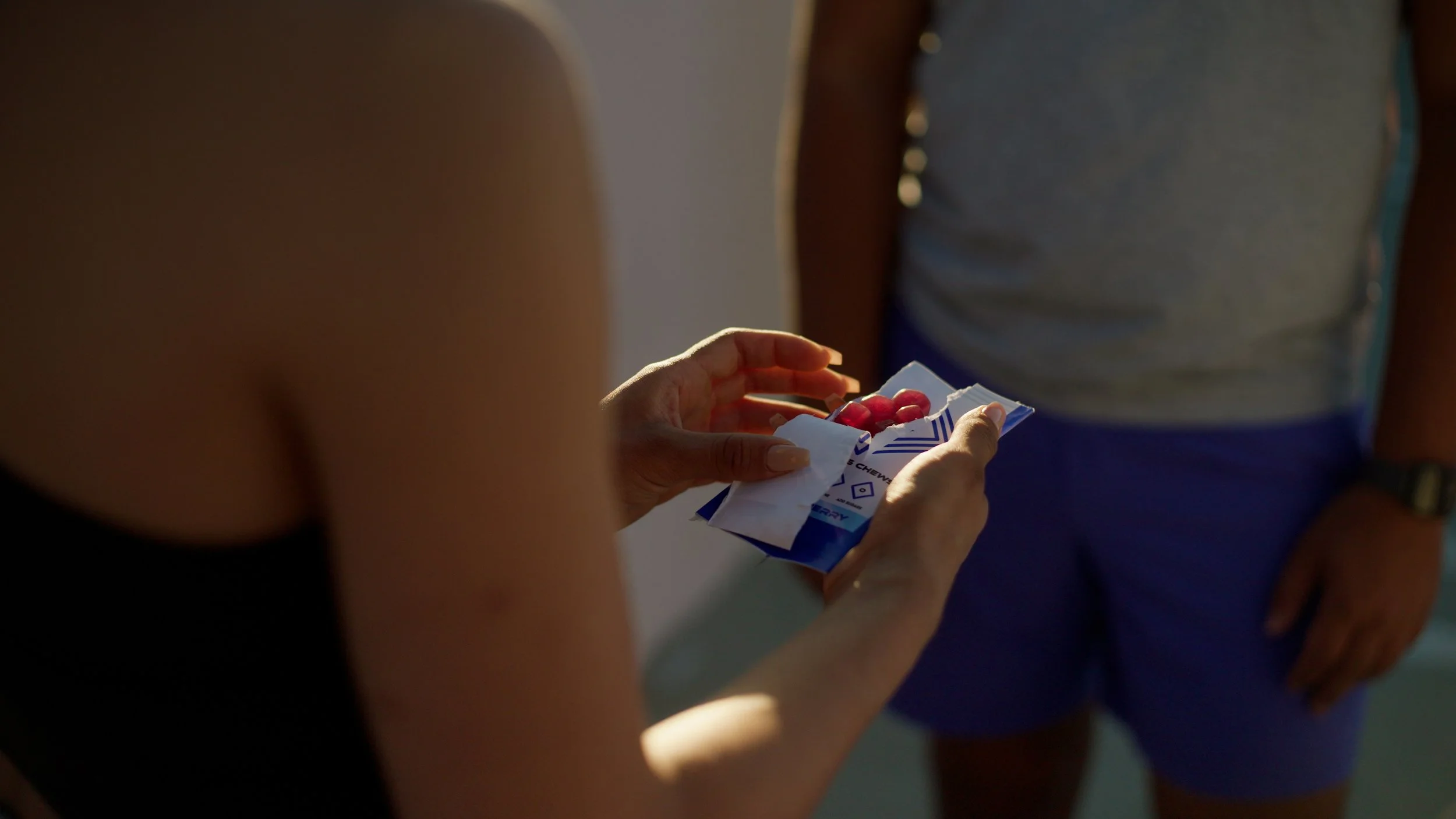 Person holding prescription medication packet with red pills indoors.