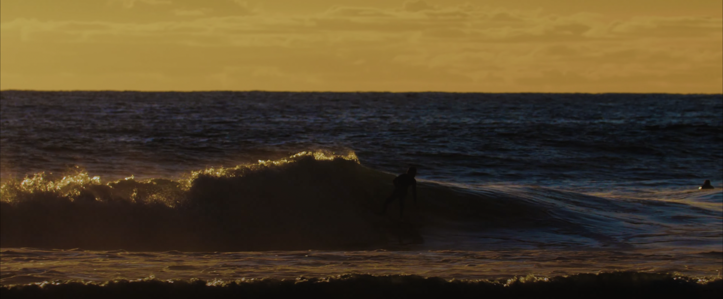 Surfer riding a wave during sunset, ocean backdrop