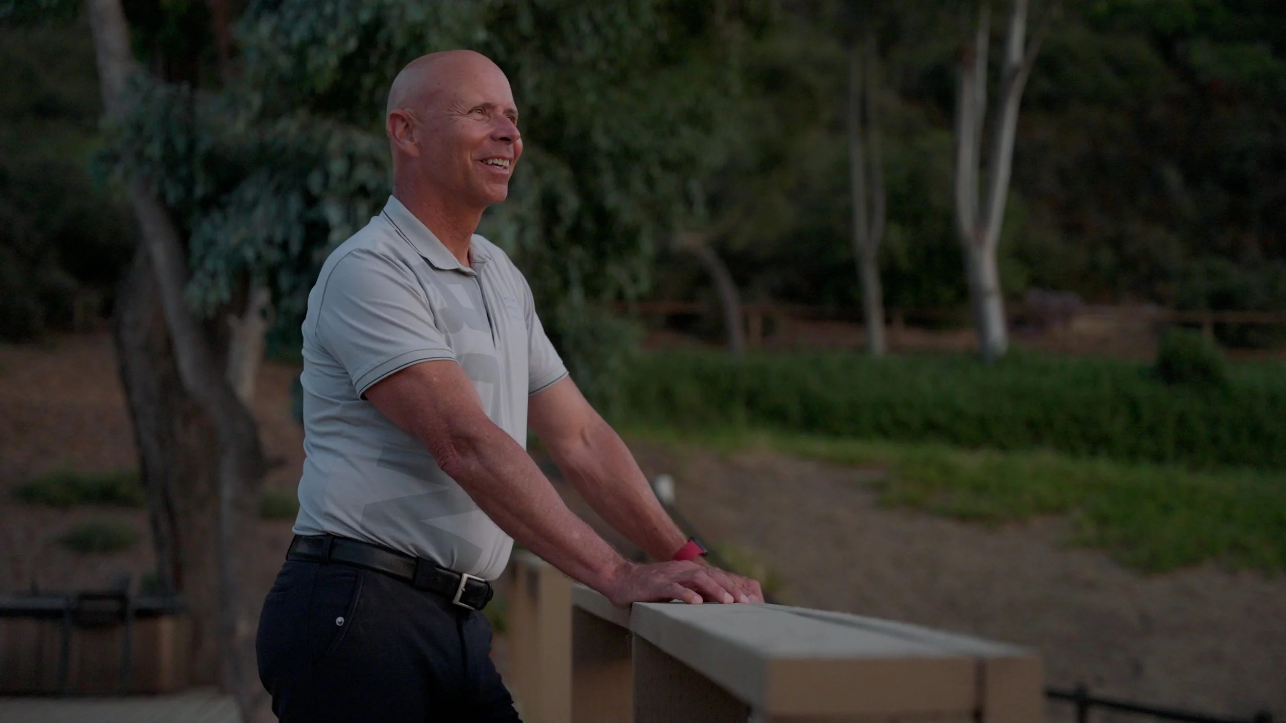 Man in short-sleeve shirt leaning on railing outdoors