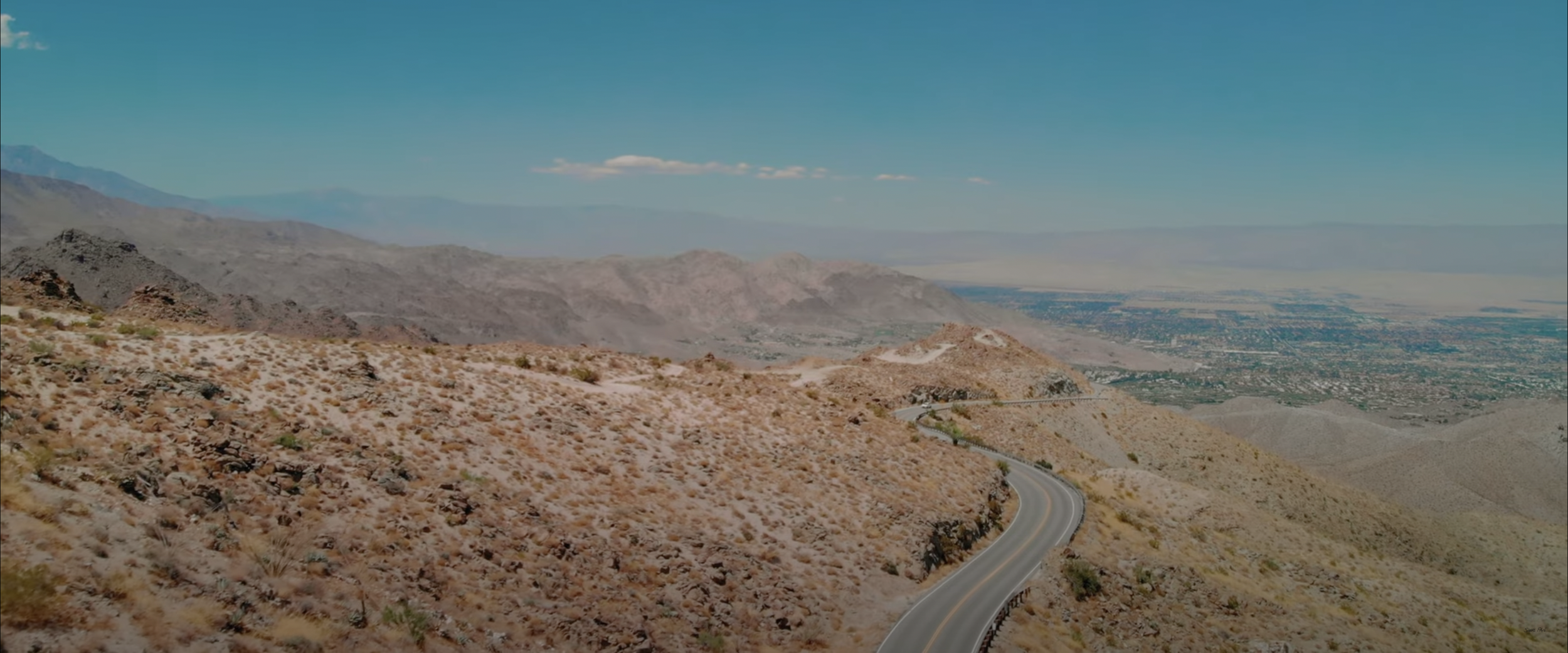 Desert landscape with winding road and mountains under clear blue sky