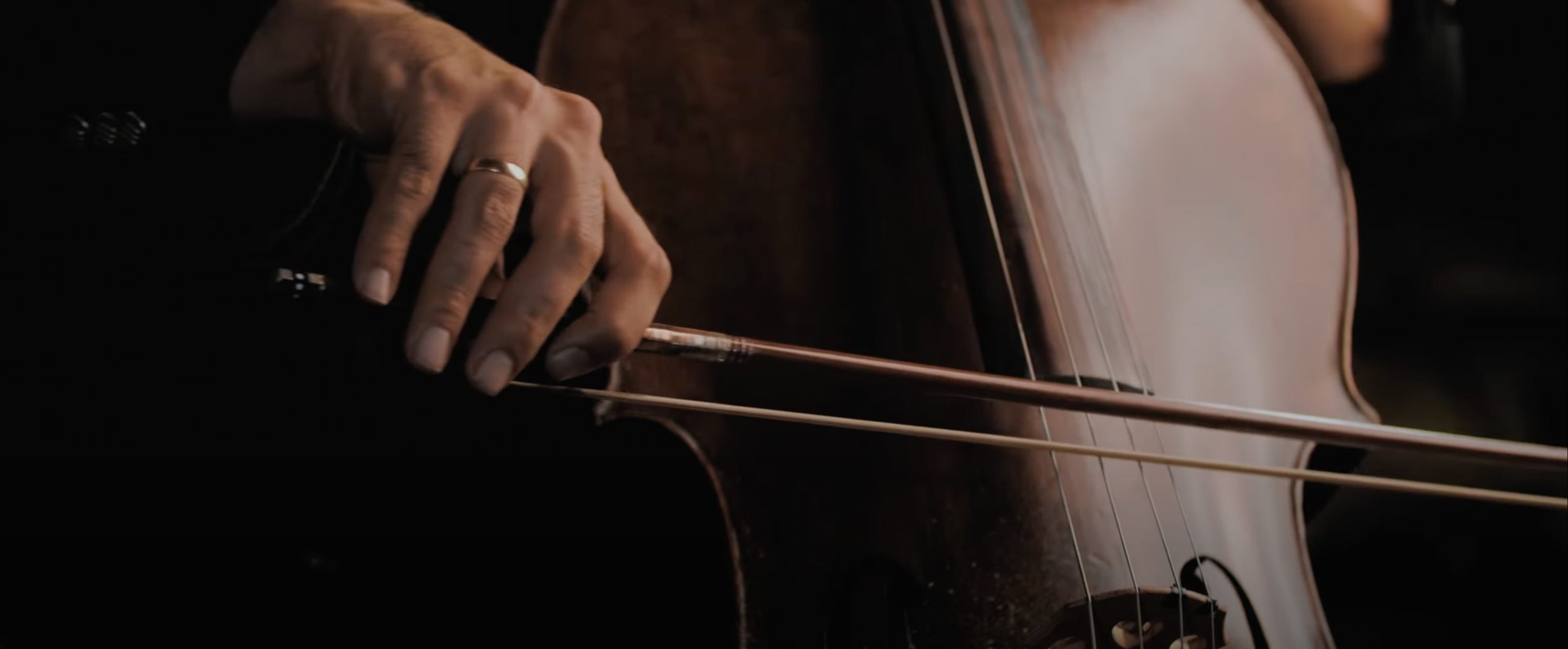 Close-up of a person playing a cello with a bow.