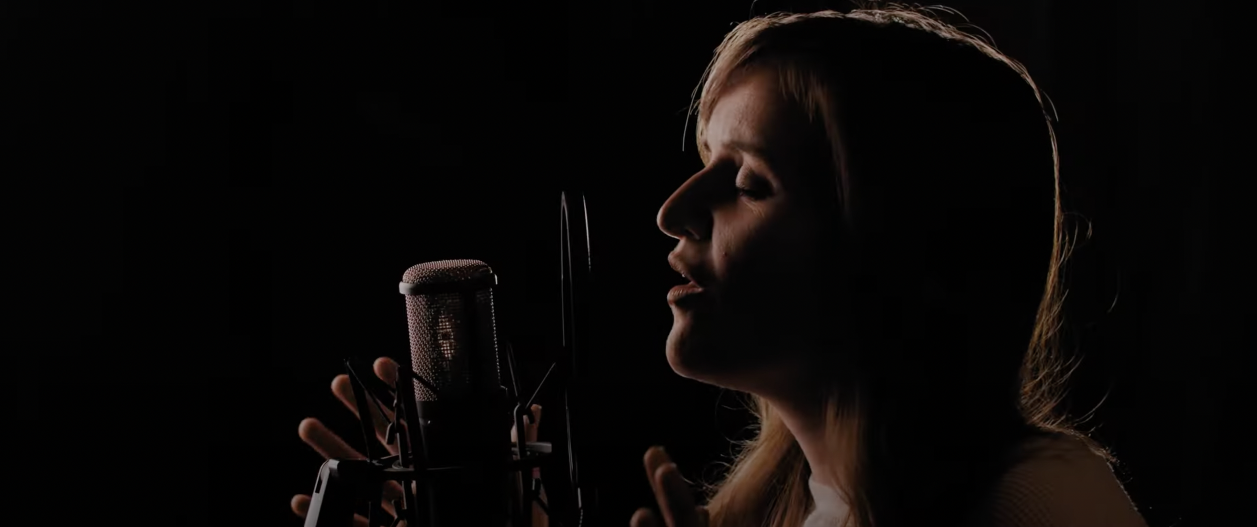 Woman singing into a microphone in low light