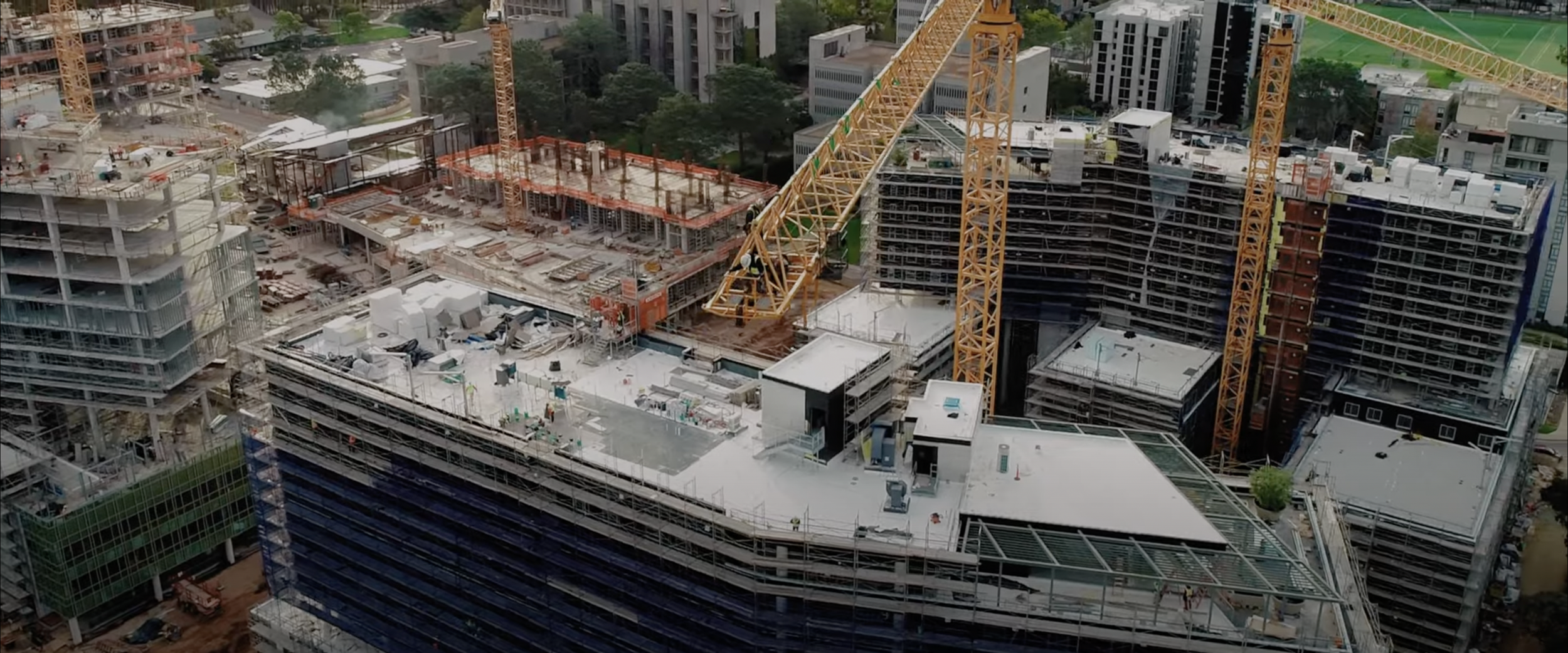 Aerial view of a construction site with cranes and partially constructed buildings.