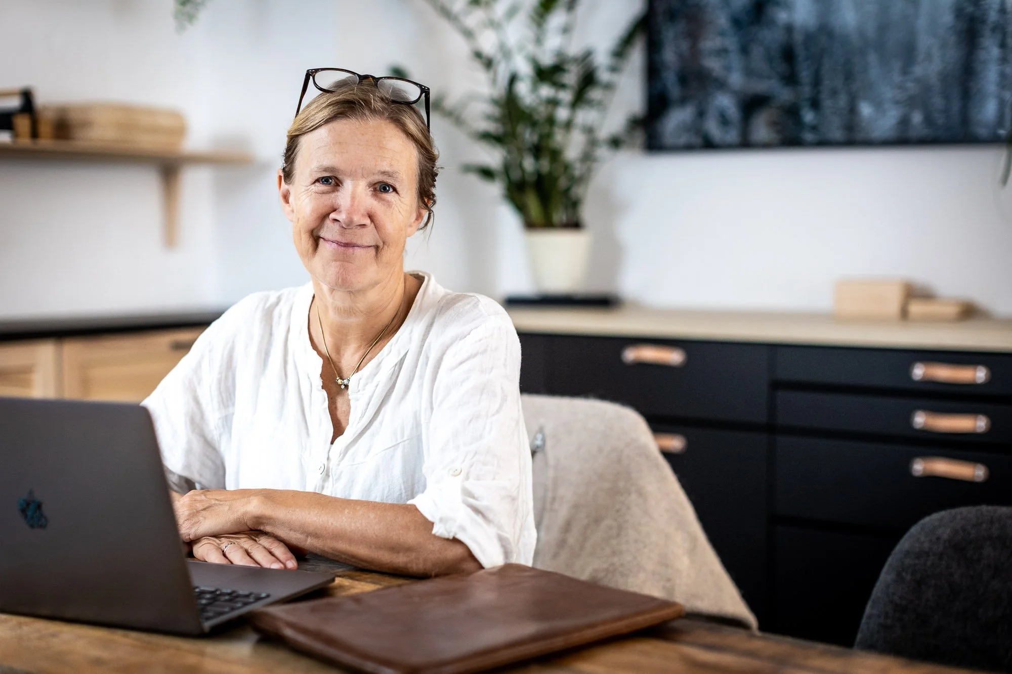 Åsa Strandberg, grundare av företaget Respin, sitter vid ett bord med en dator framför sig. Hon bär en vit linneskjorta och har ett par glasögon uppskjutna på huvudet.
