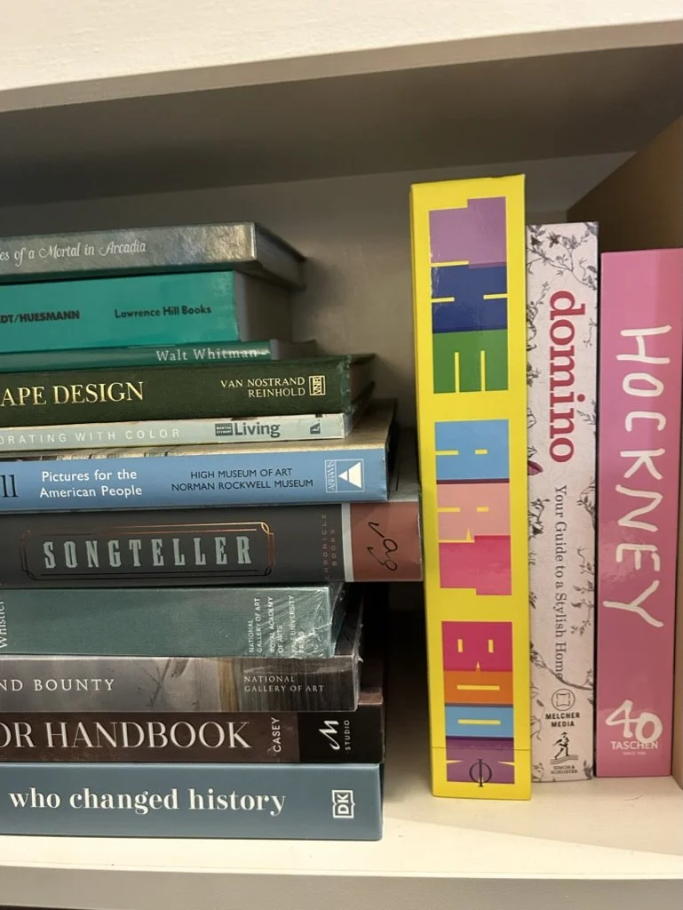 Shelf of various books, with a colorful sign spelling 'VIELE' in multicolor letters on a yellow background.