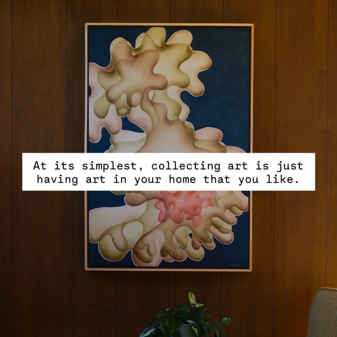 An abstract painting with organic, interconnected shapes in neutral tones on a dark blue background, framed and hung on a wooden wall, with a potted plant visible at the bottom.