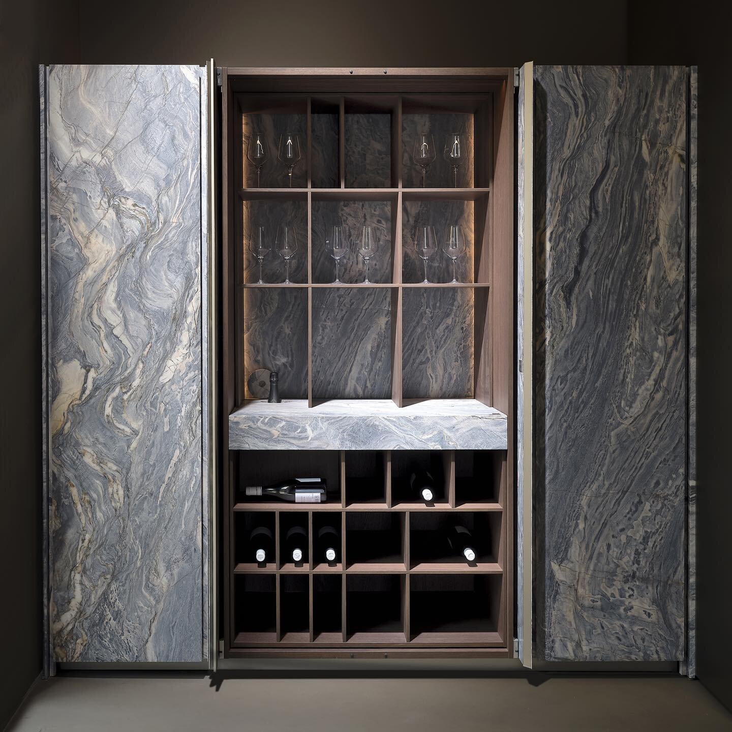 A wall of luxurious Blue explosion natural stone, conceals an area suitable for wine lovers, complete with a customizable wine rack which can also be used as a wine tasting area. These tall stone doors, available in various heights, furthers our phil
