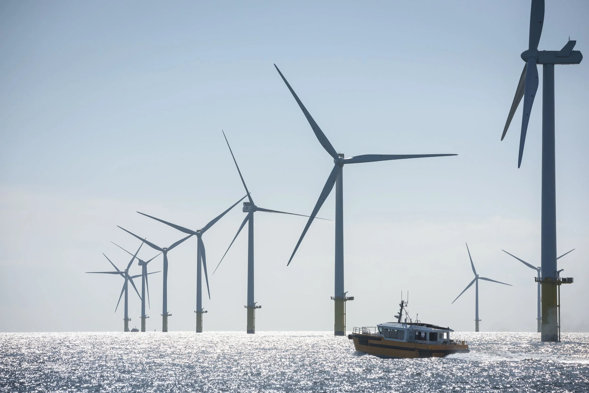 Offshore wind turbines with a boat on the ocean.