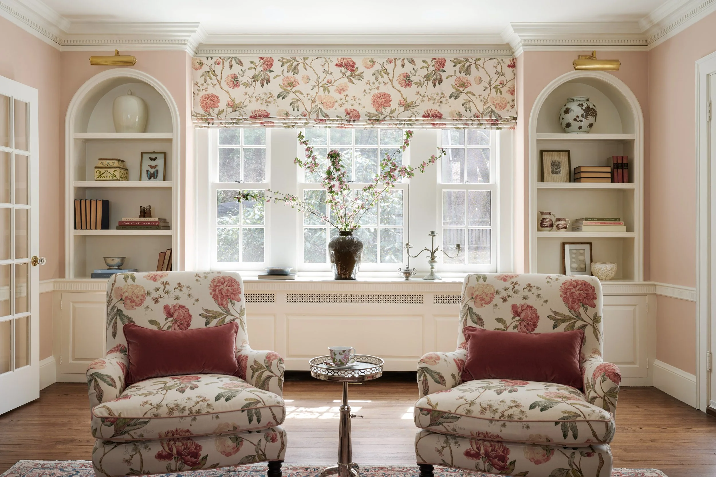 builtin bookshelves and layered floral fabrics pink walls