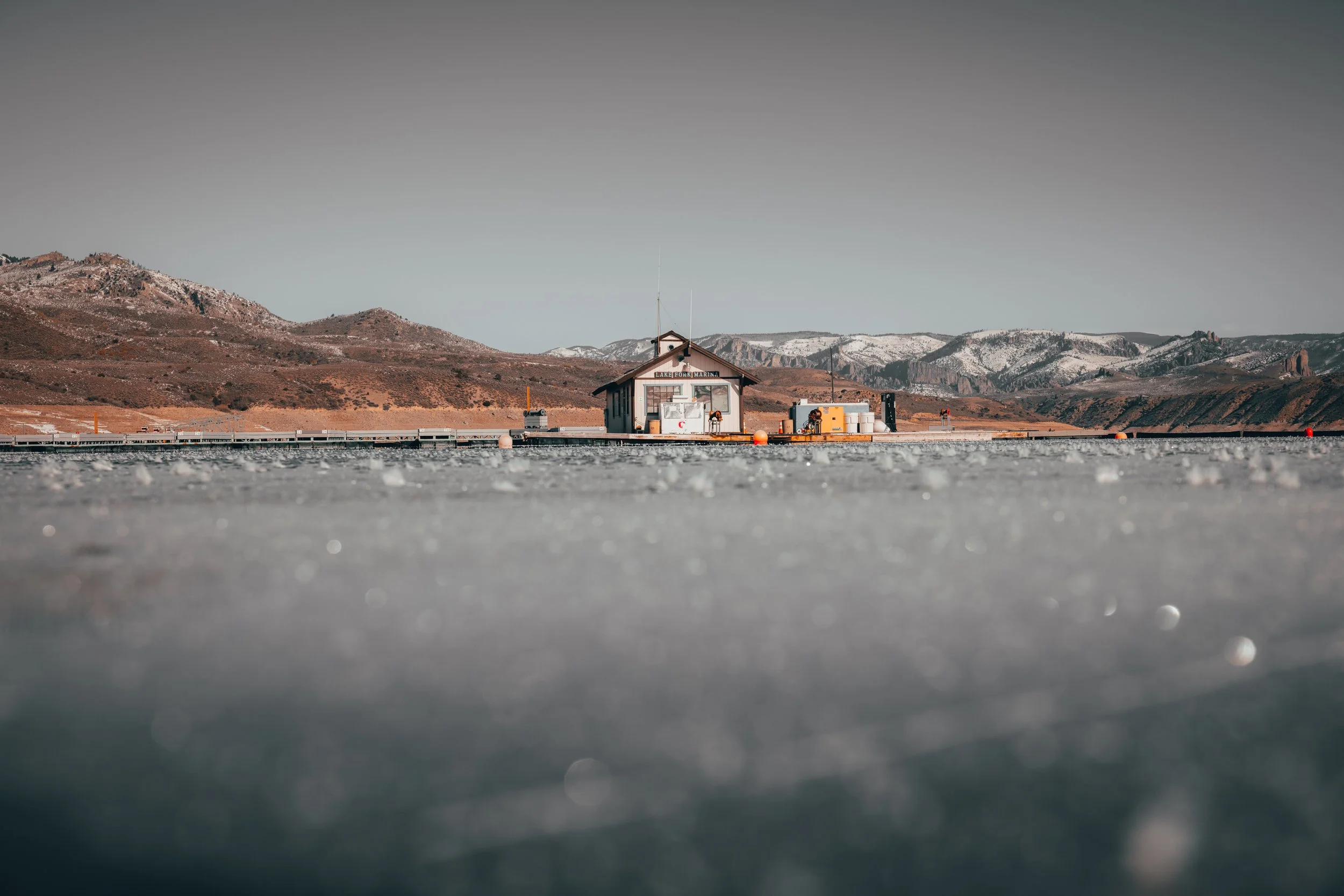 Small shack on a snowy pier with mountainous background