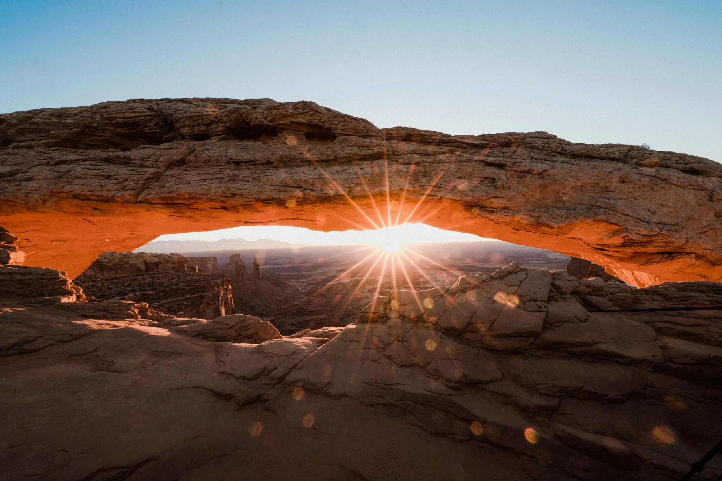 Mesa Arch at sunrise, Canyonlands National Park, Utah, with sun rays visible through the arch opening.