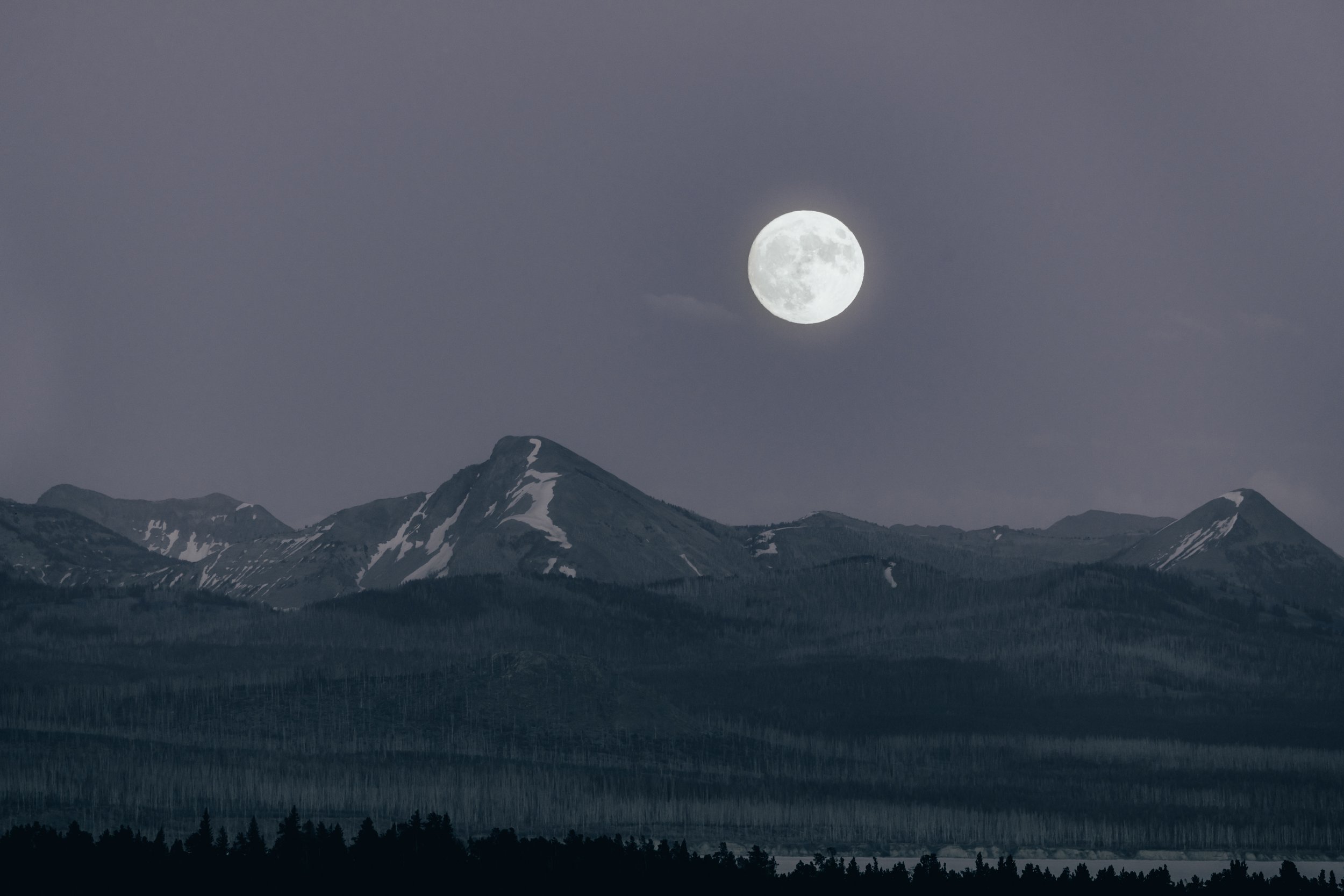 Full moon over mountain range at night.