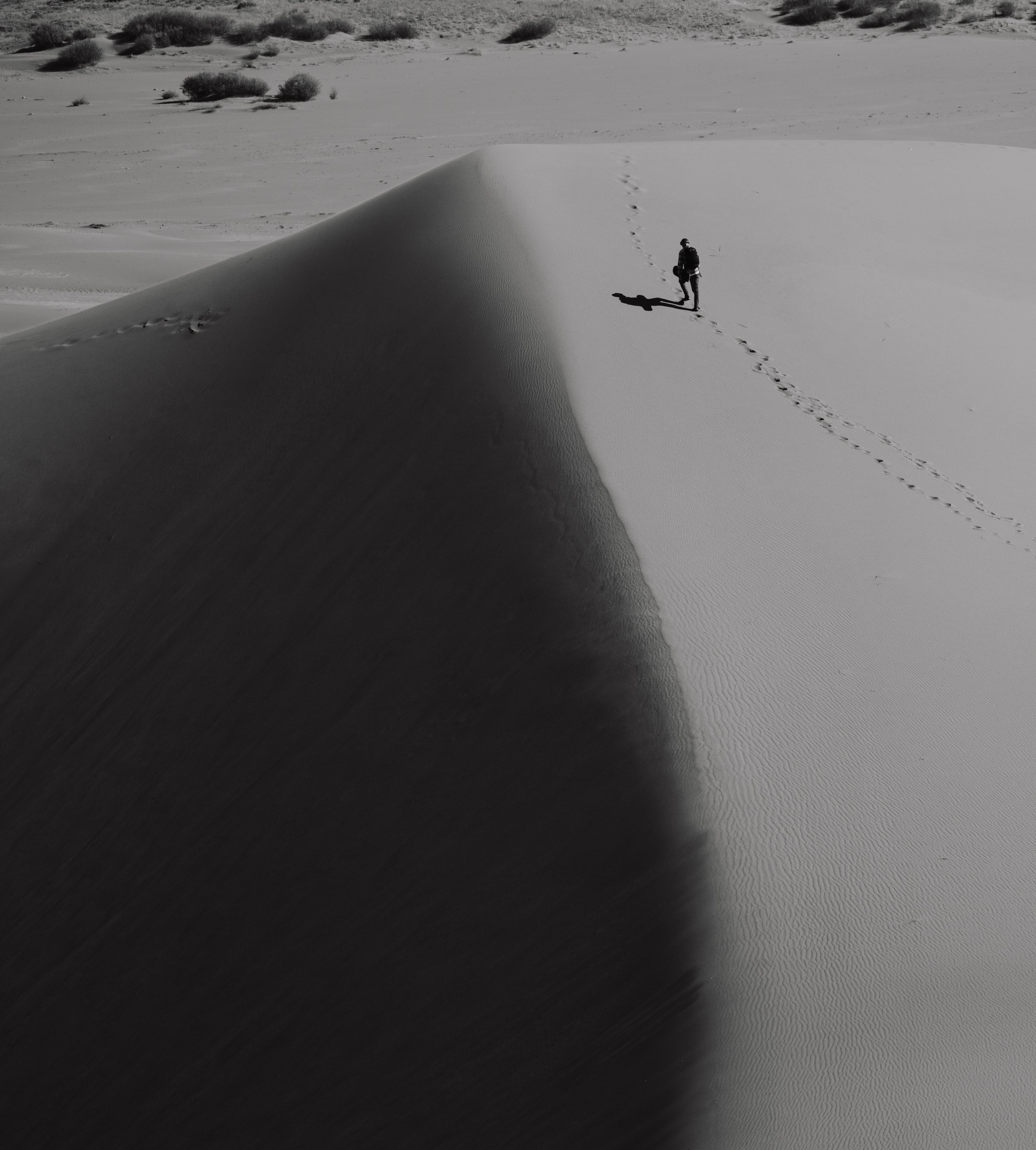 Person walking on sand dune with footsteps in desert landscape