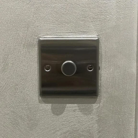 Close-up of a metallic switch or button mounted on a wall.
