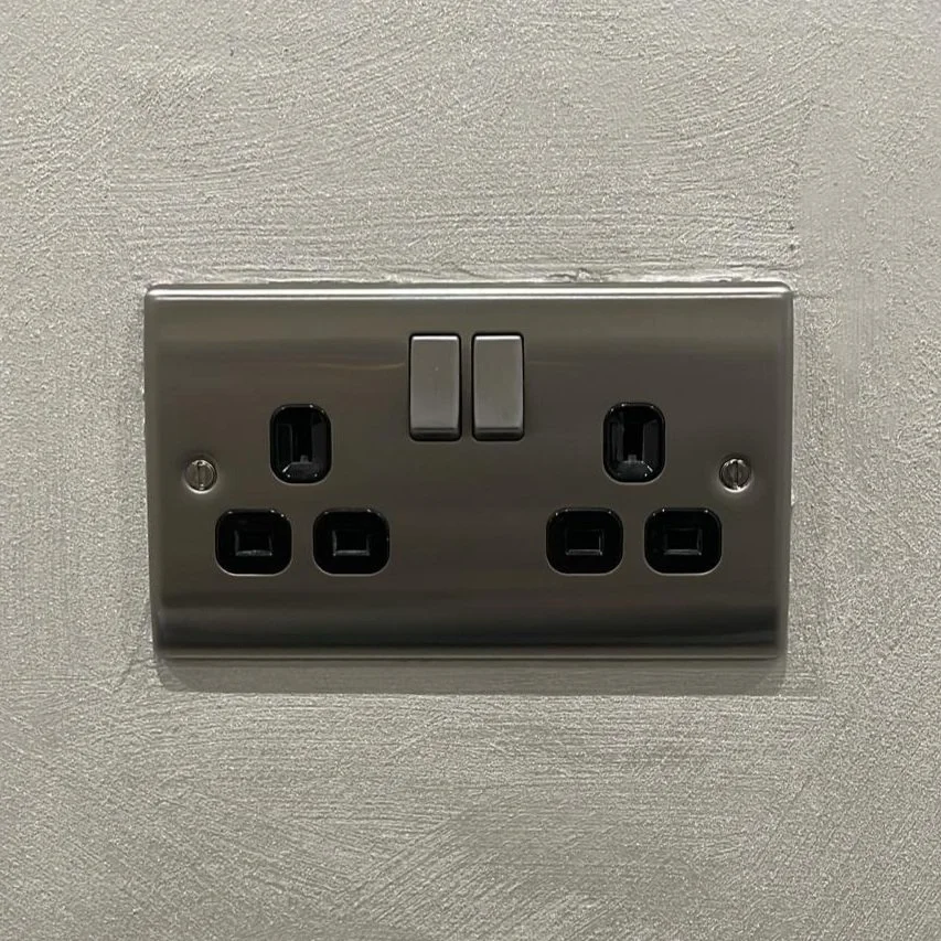 Double electrical wall socket with two switches, mounted on a textured wall.