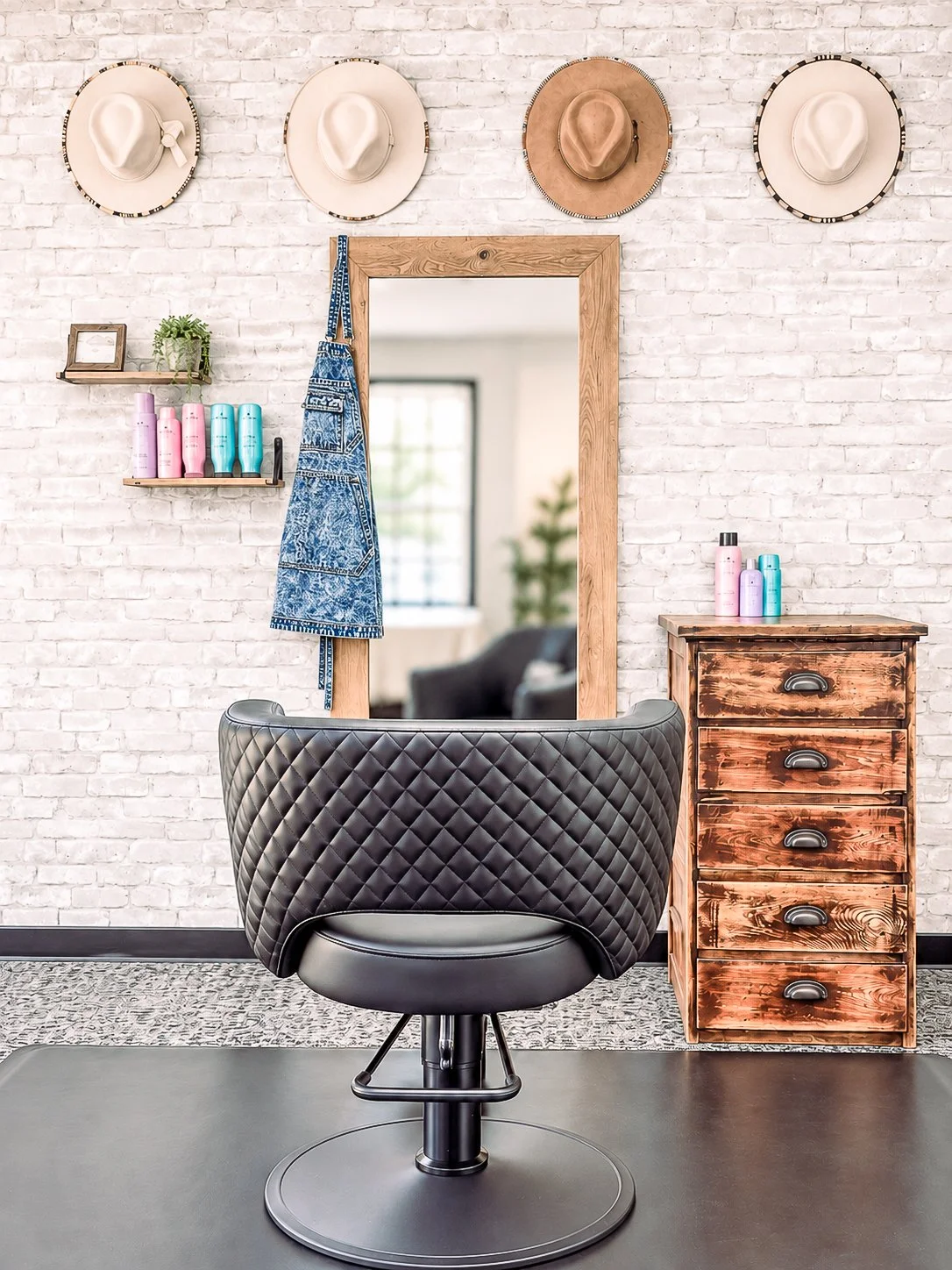 Salon styling chair and wood-framed mirror at White Oak & Co hair studio in Byron, IL, with hats and products on display