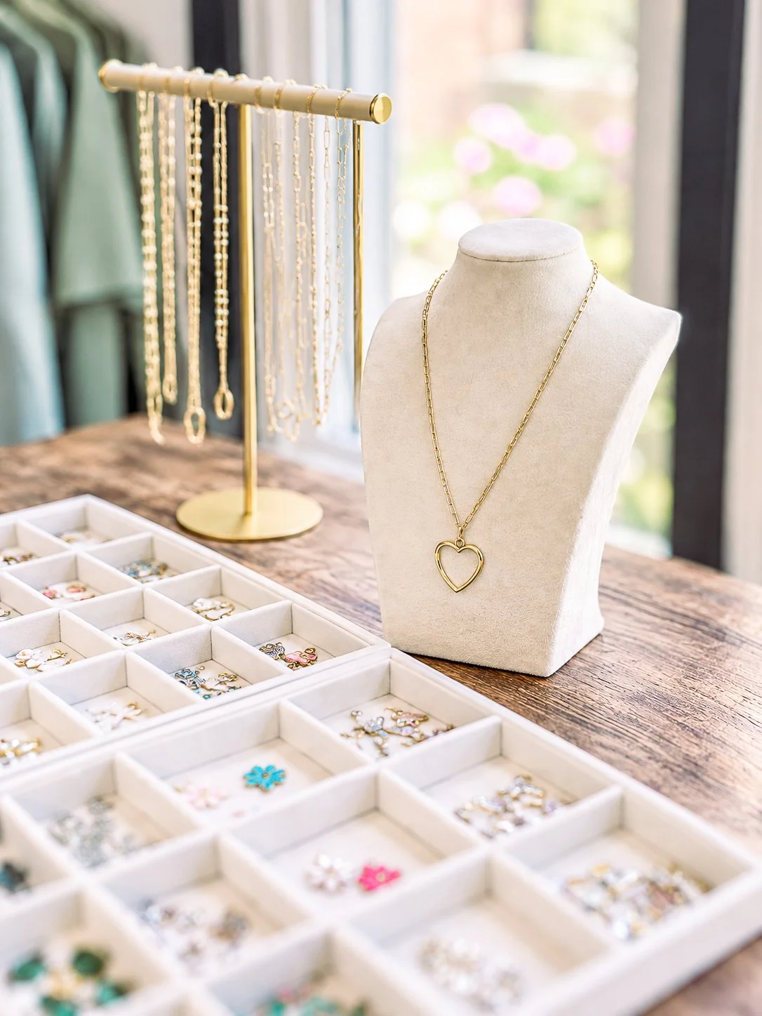 Charm bar at White Oak & Co with gold chain necklaces and velvet trays of charms for build-your-own jewelry parties