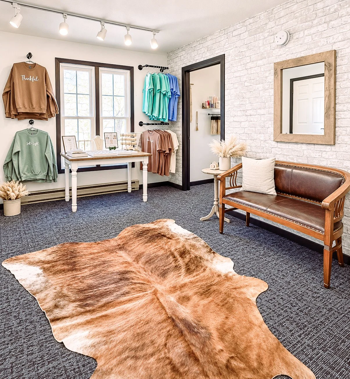 Boutique shopping room at White Oak & Co in Byron, IL with graphic sweatshirts, tees, jewelry table, and leather bench
