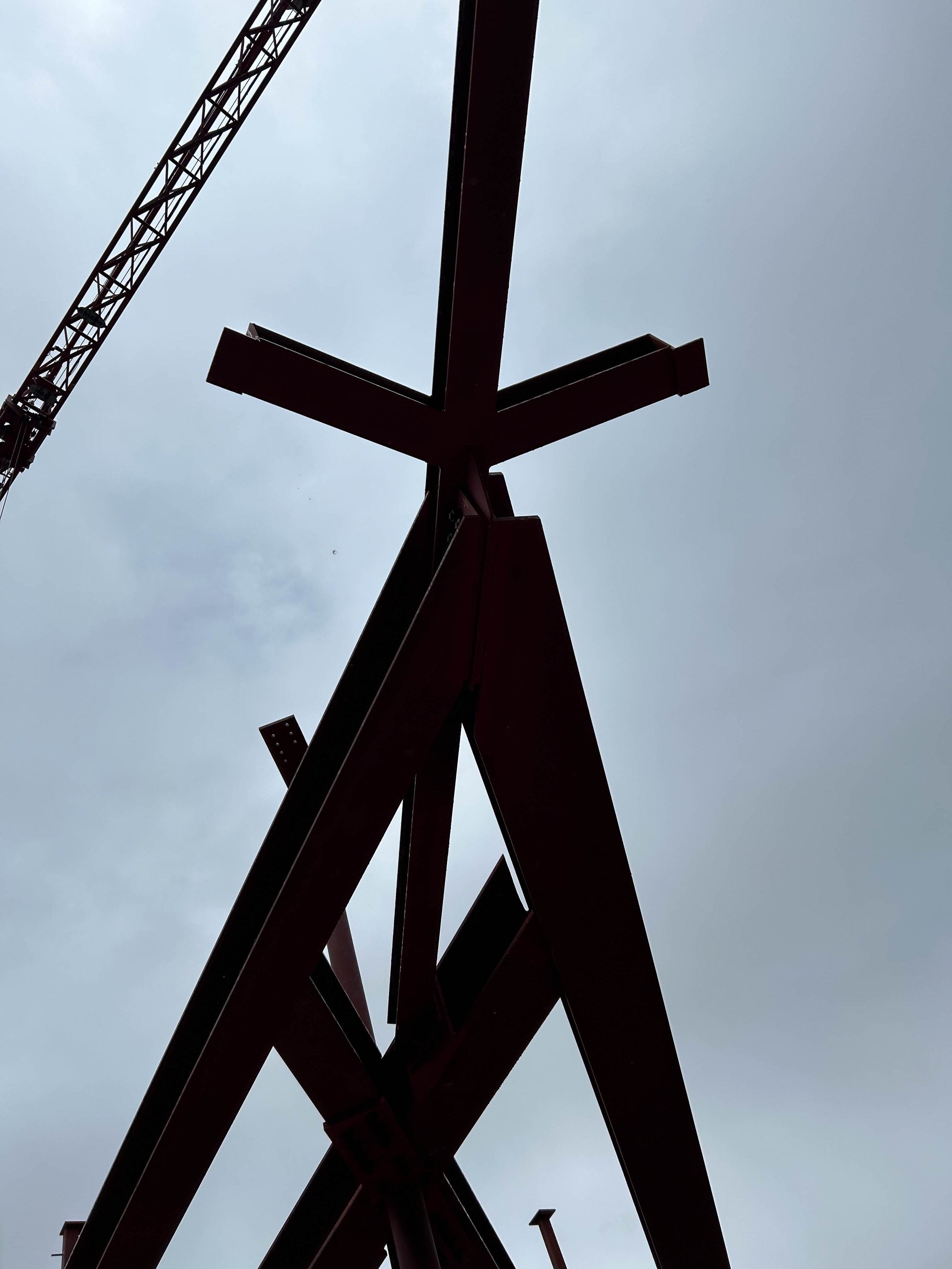 Steel construction framework on a construction site under an overcast sky.