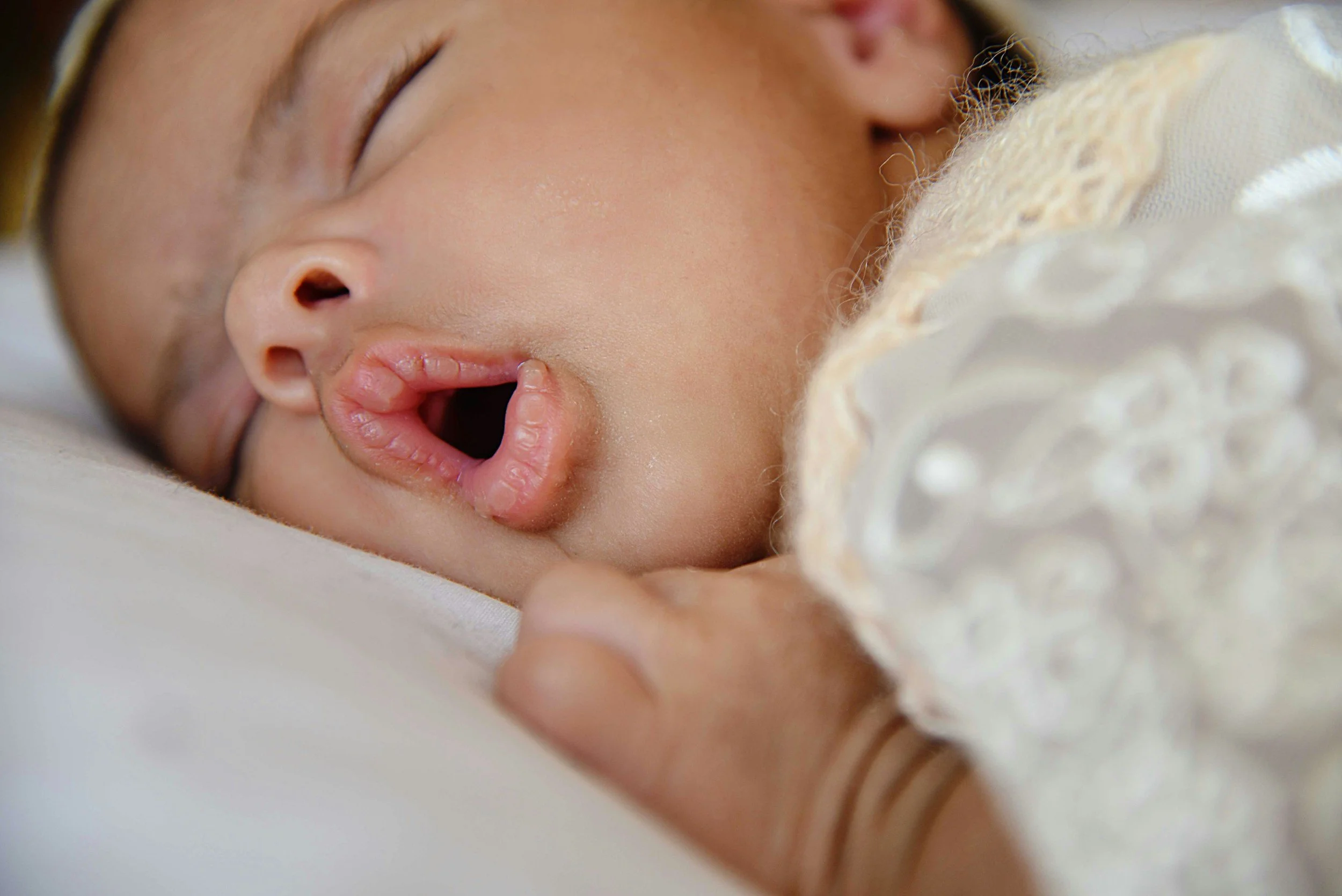 Tongue tied baby sleeping on their stomach with their mouth open