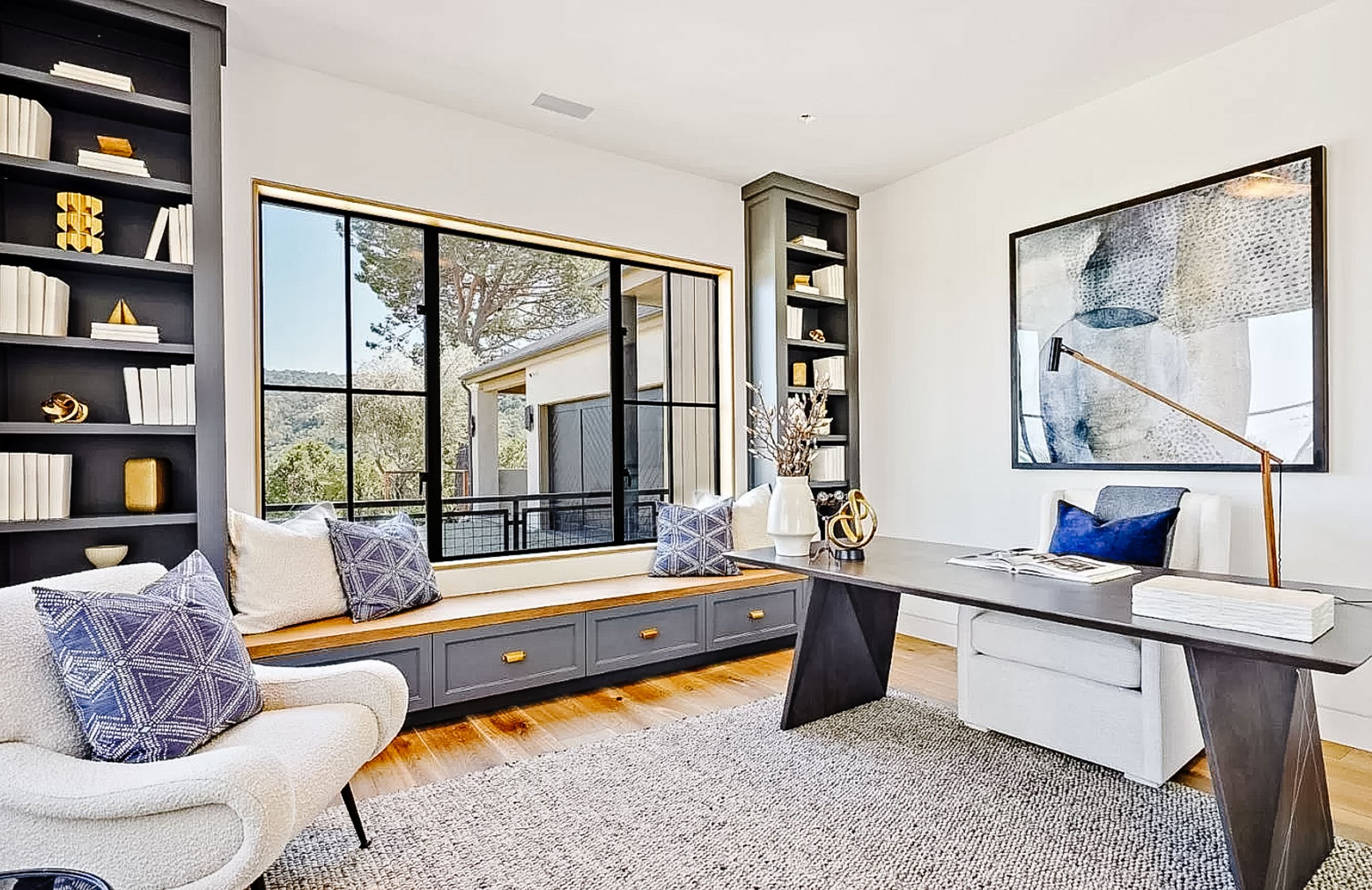 Main-level office, entered via sliding glass doors off the foyer, features banquette seating and built-in library shelves